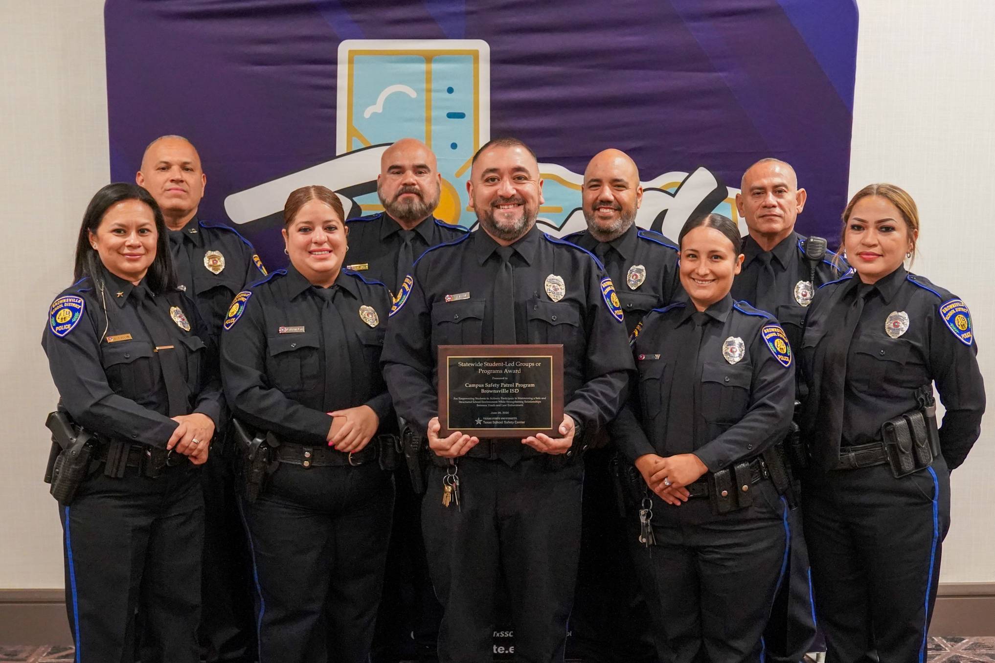 large group of police officers posing for photo with award plaque