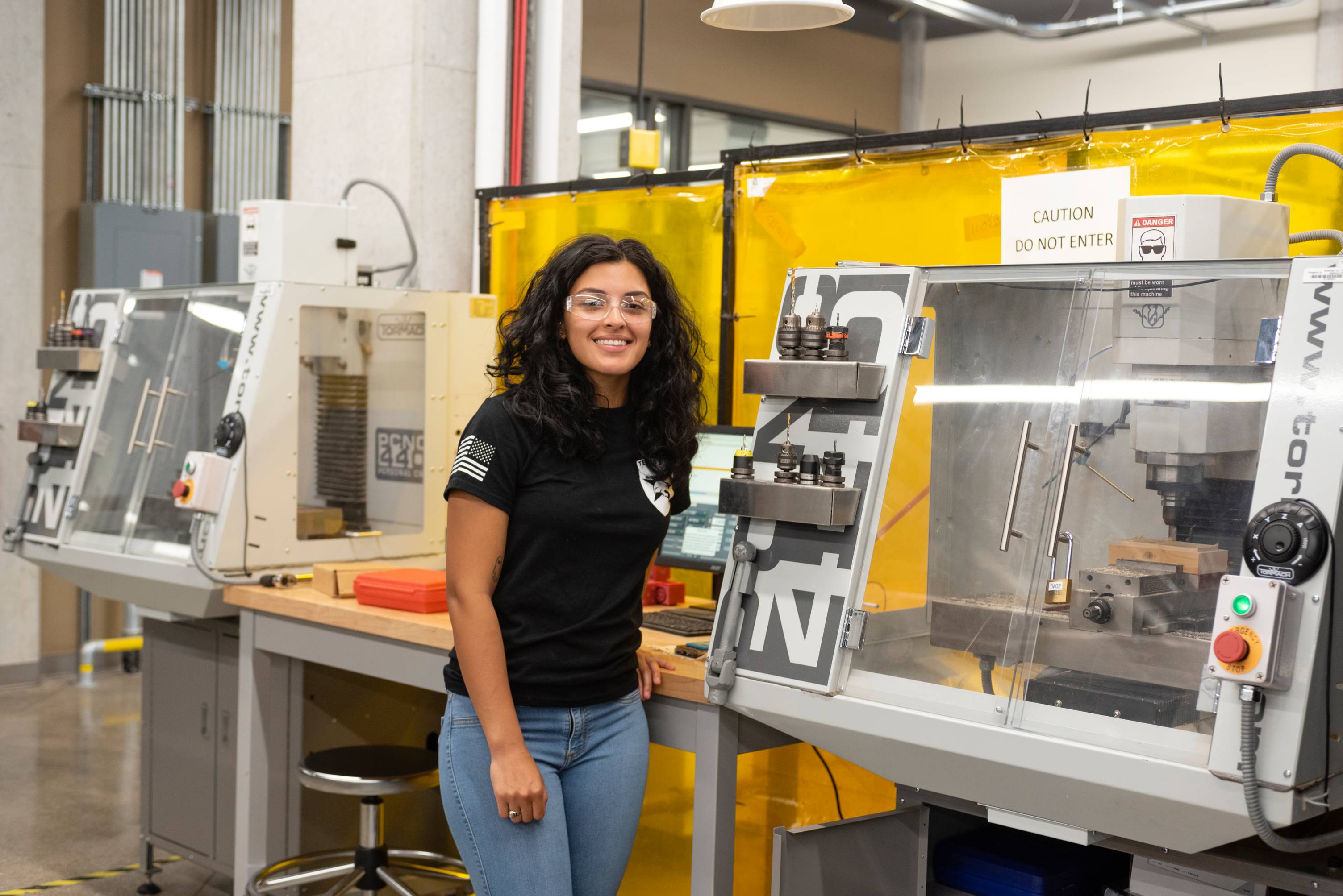 A woman smiles a the camera in an engineering lab. 