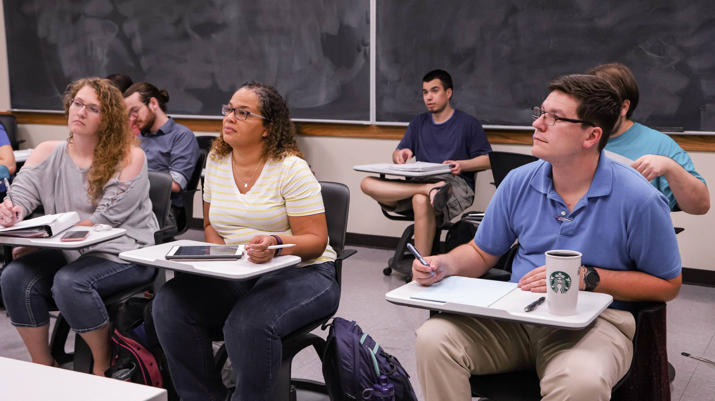 Students in a classroom sit and look forward attentively.