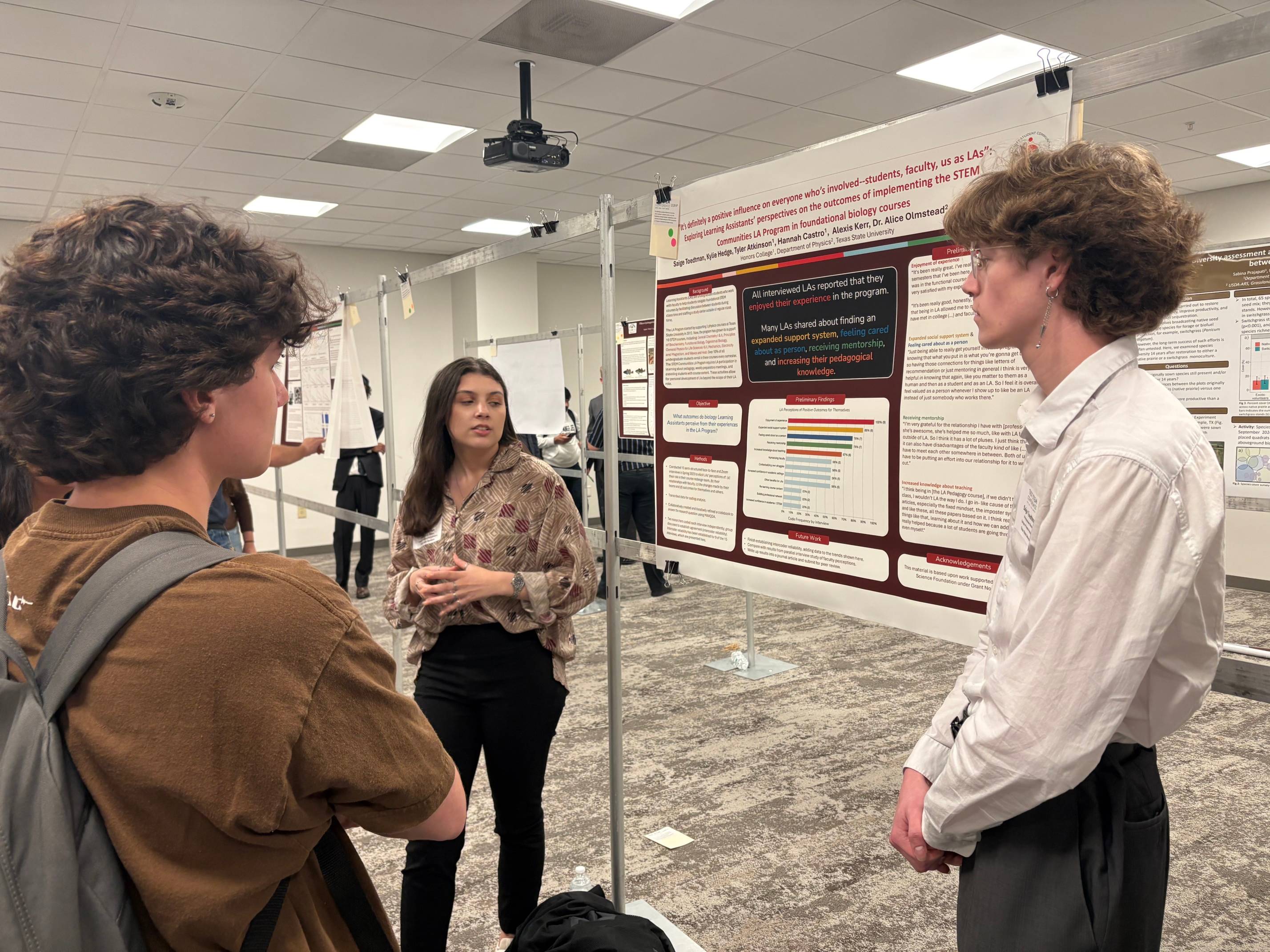 Two undergraduates telling another student about their research poster. 