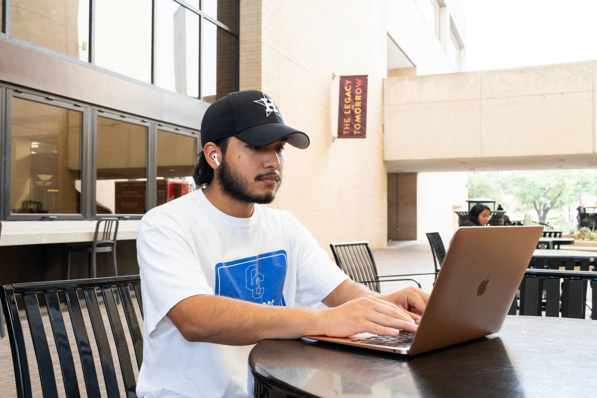 Student sitting outside on laptop with headphones in