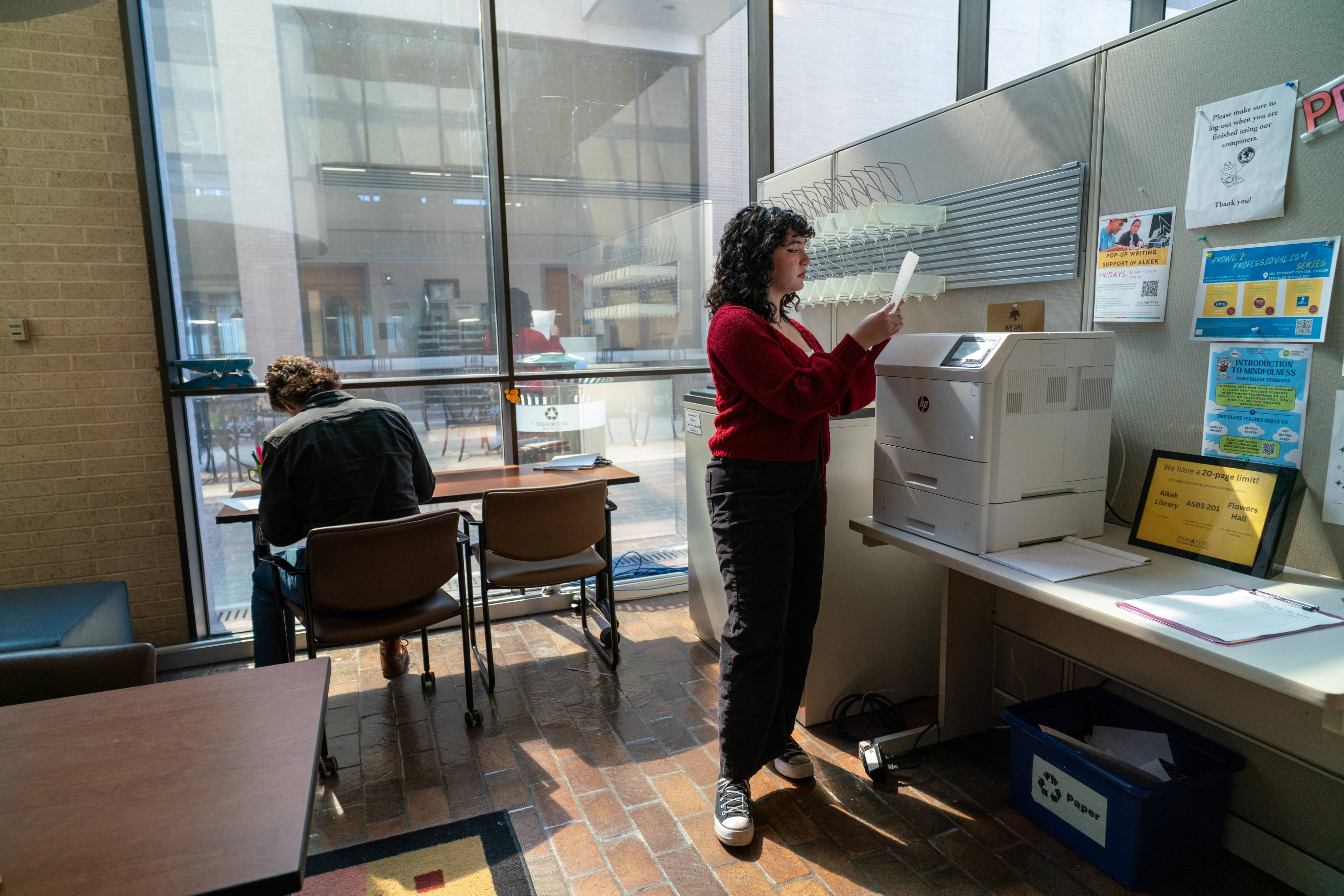 a person standing at a printer in an office