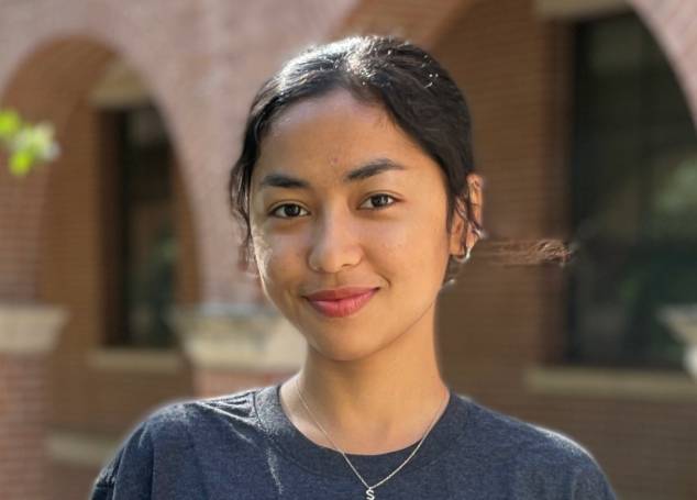 Photo of Sampada Niroula standing in from of arches, wearing an IDEA Center t-shirt