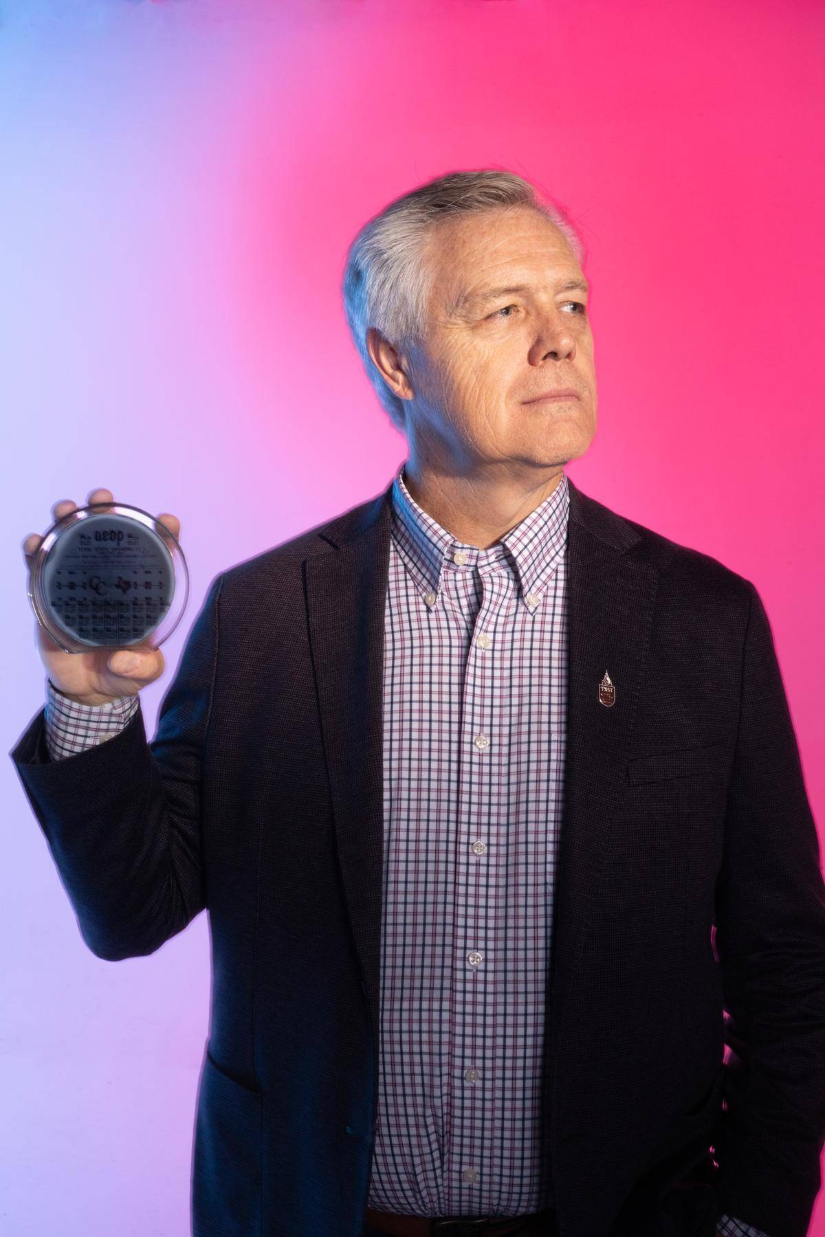 man holding up semiconductor in right hand as he looks off to his left