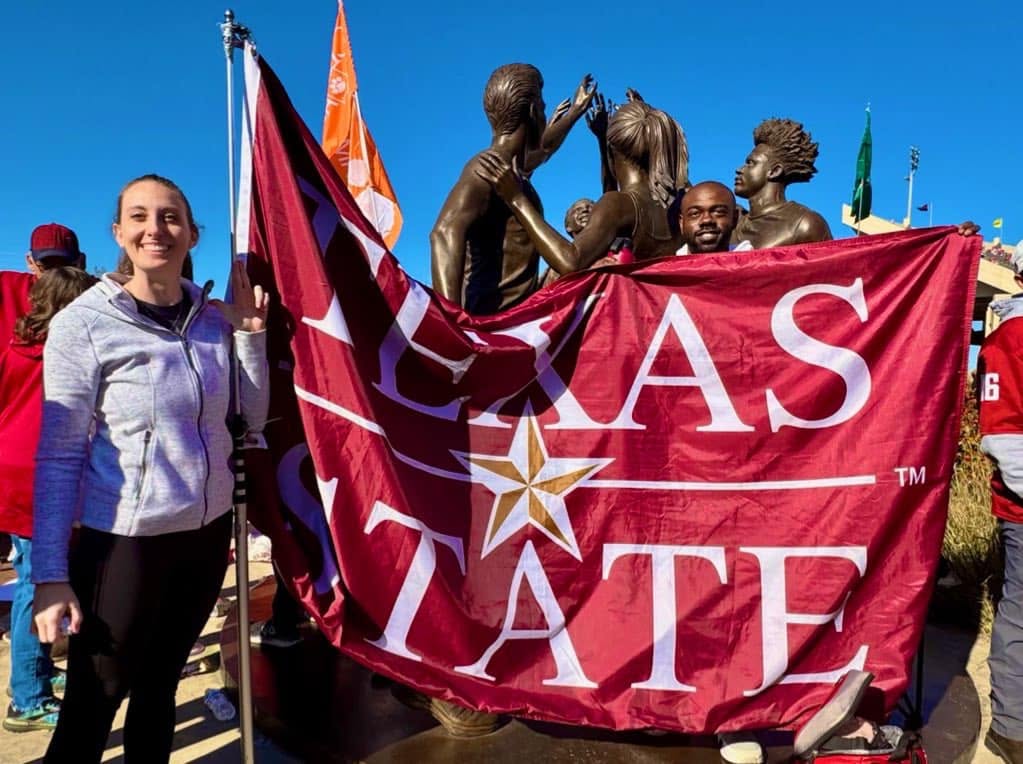 Two Texas State alumni holding a Texas State flag