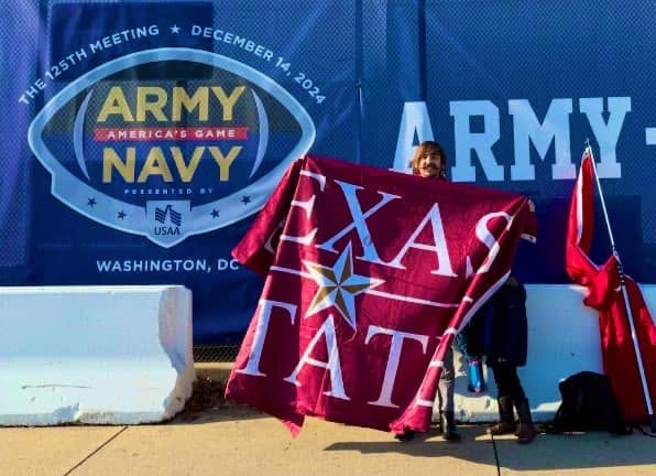 A Texas State alum holding a Texas State flag