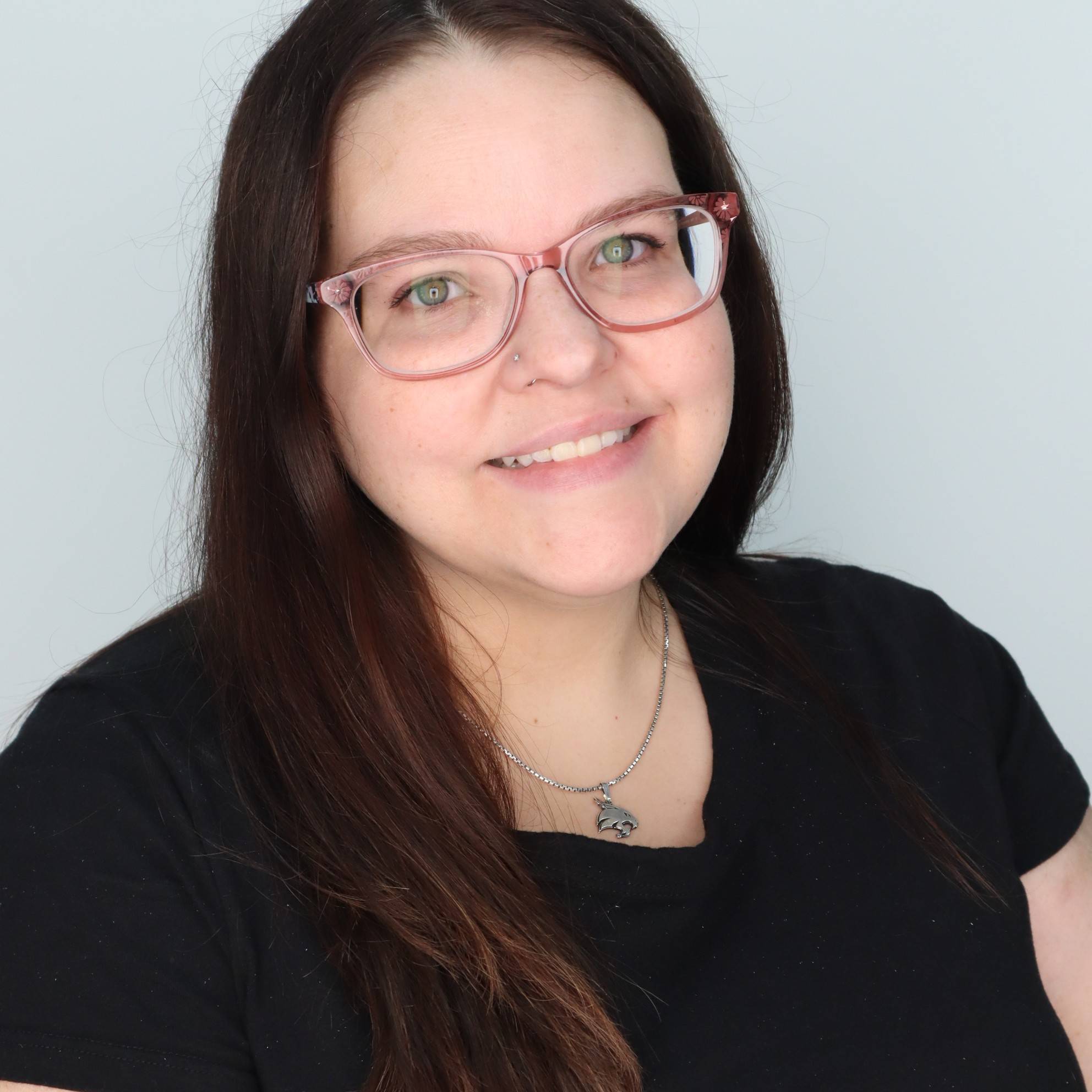 young woman with dark hair and glasses smiling at camera