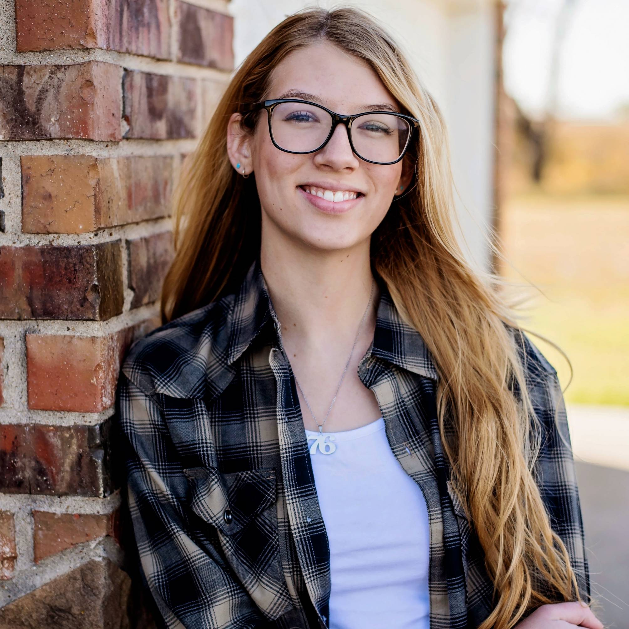 young woman with blonde hair and glasses smiling at camera