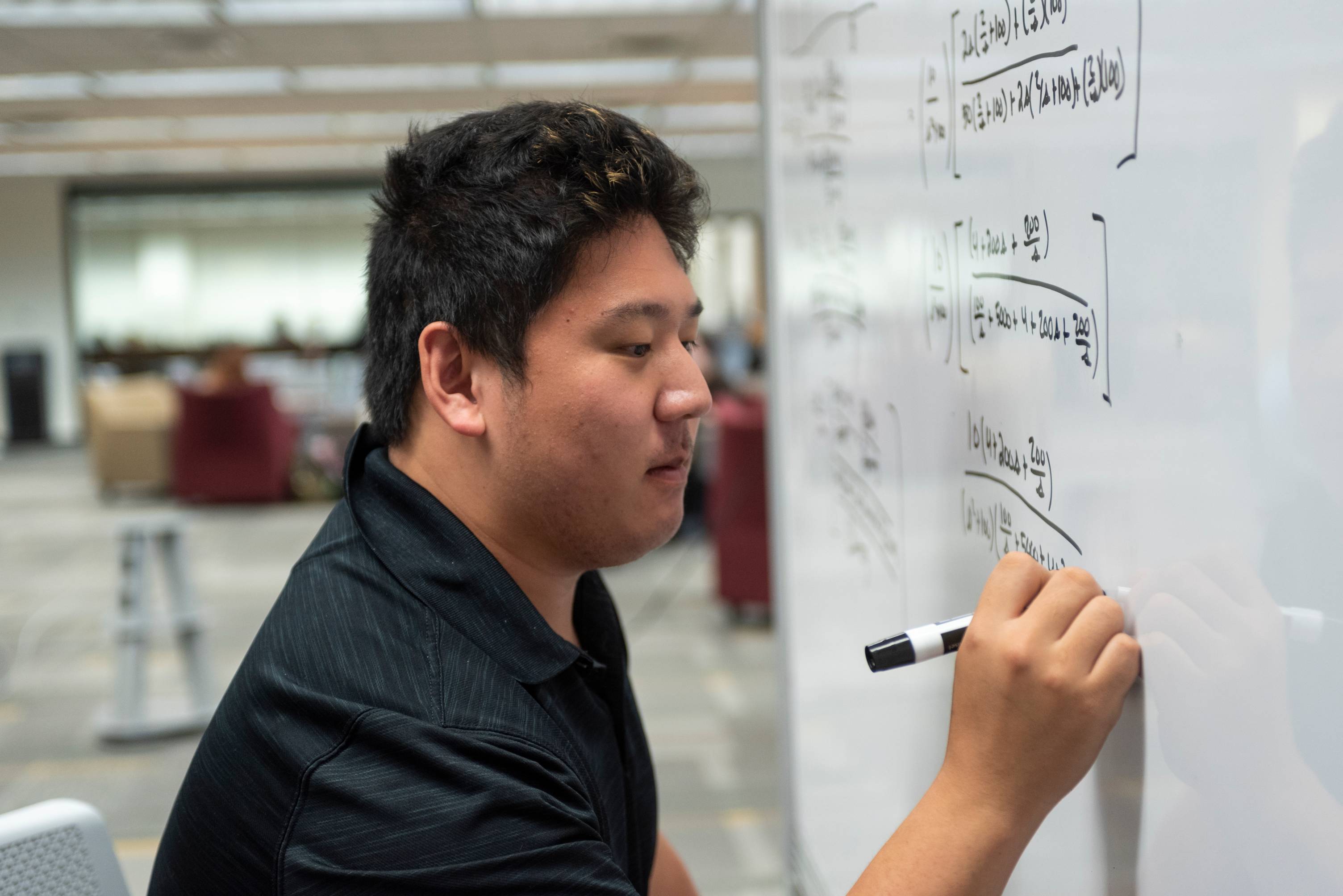 A student is writing on a whiteboard.