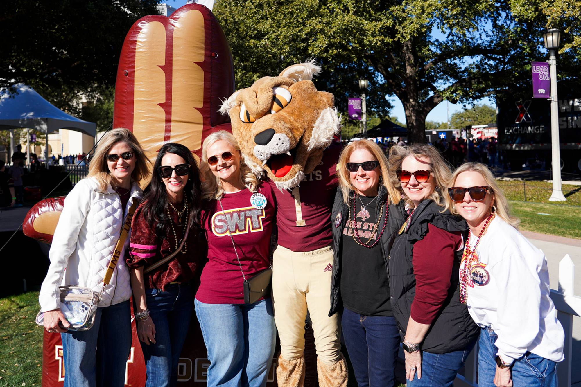 Group of Texas State fans taking a photo with Boko the Bobcat on a green space