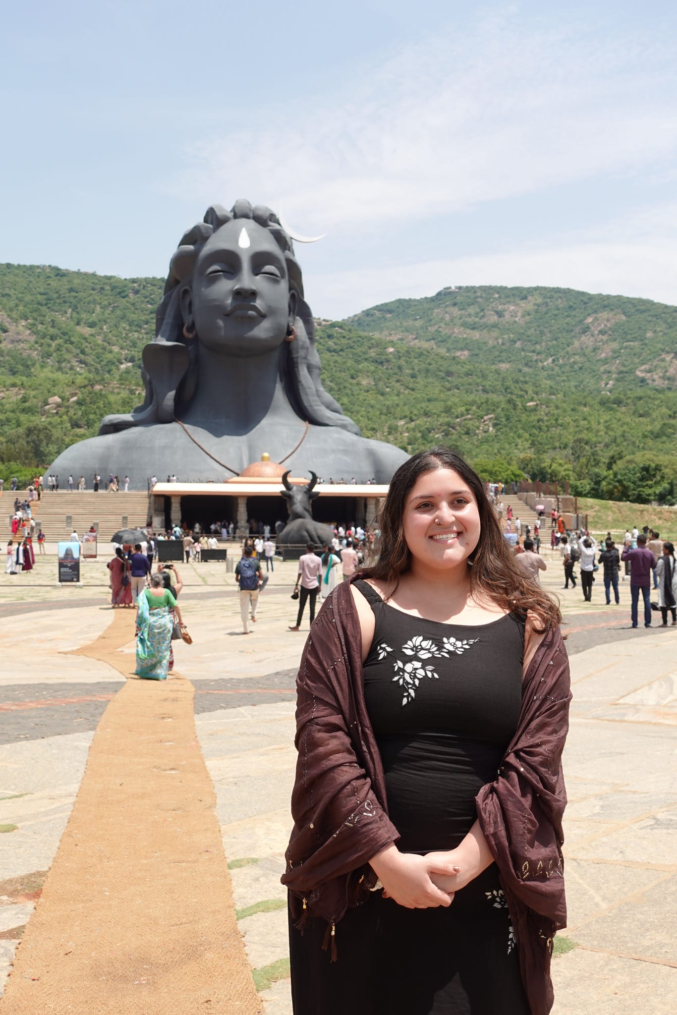 woman standing in front of large grey statue of woman's head and shoulders