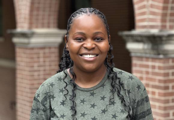 Photo of Annette, a young black woman with long curly hair. She is smiling. Her shirt is grey with stars. 