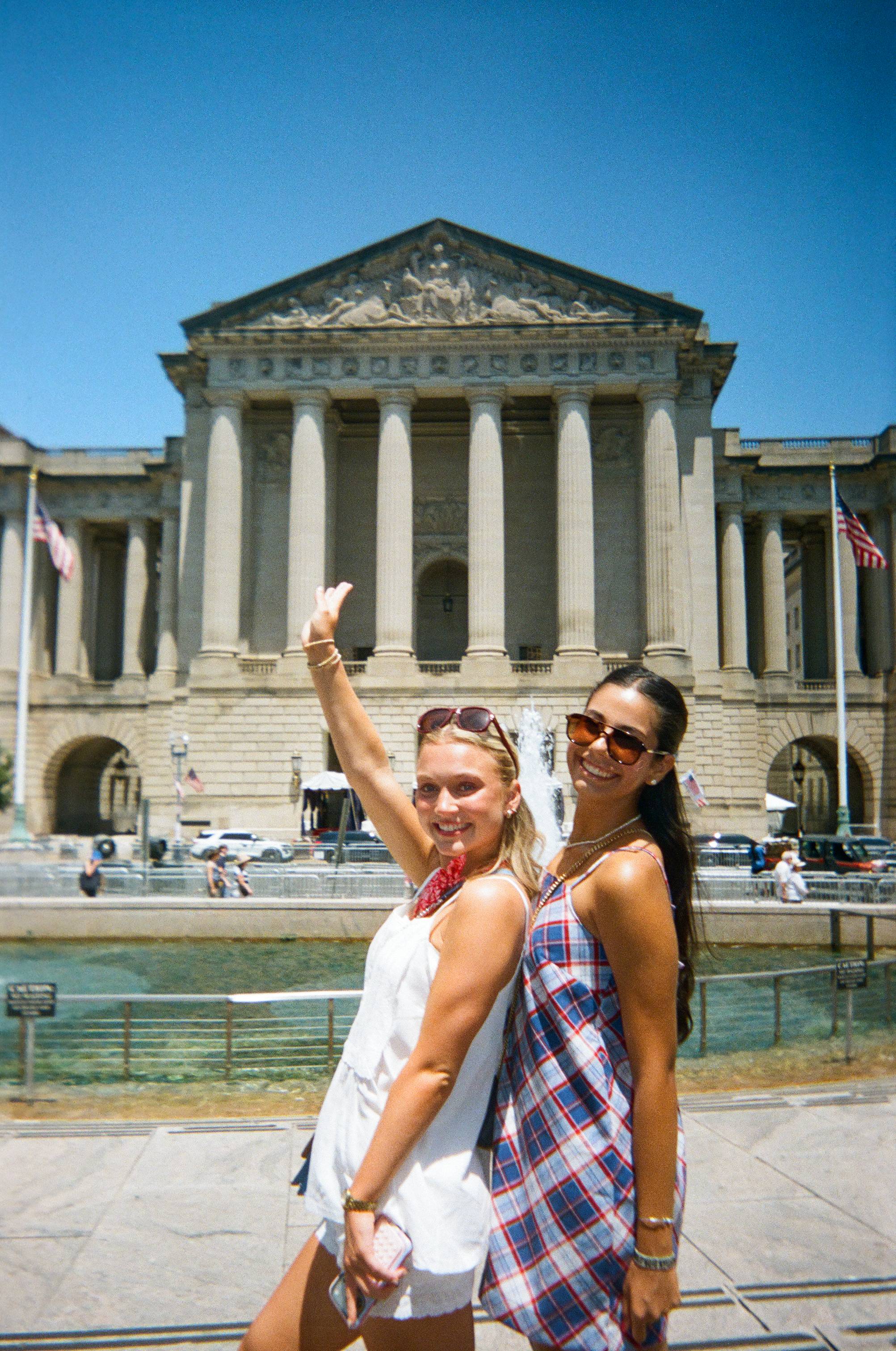 two female students pose in front of monument