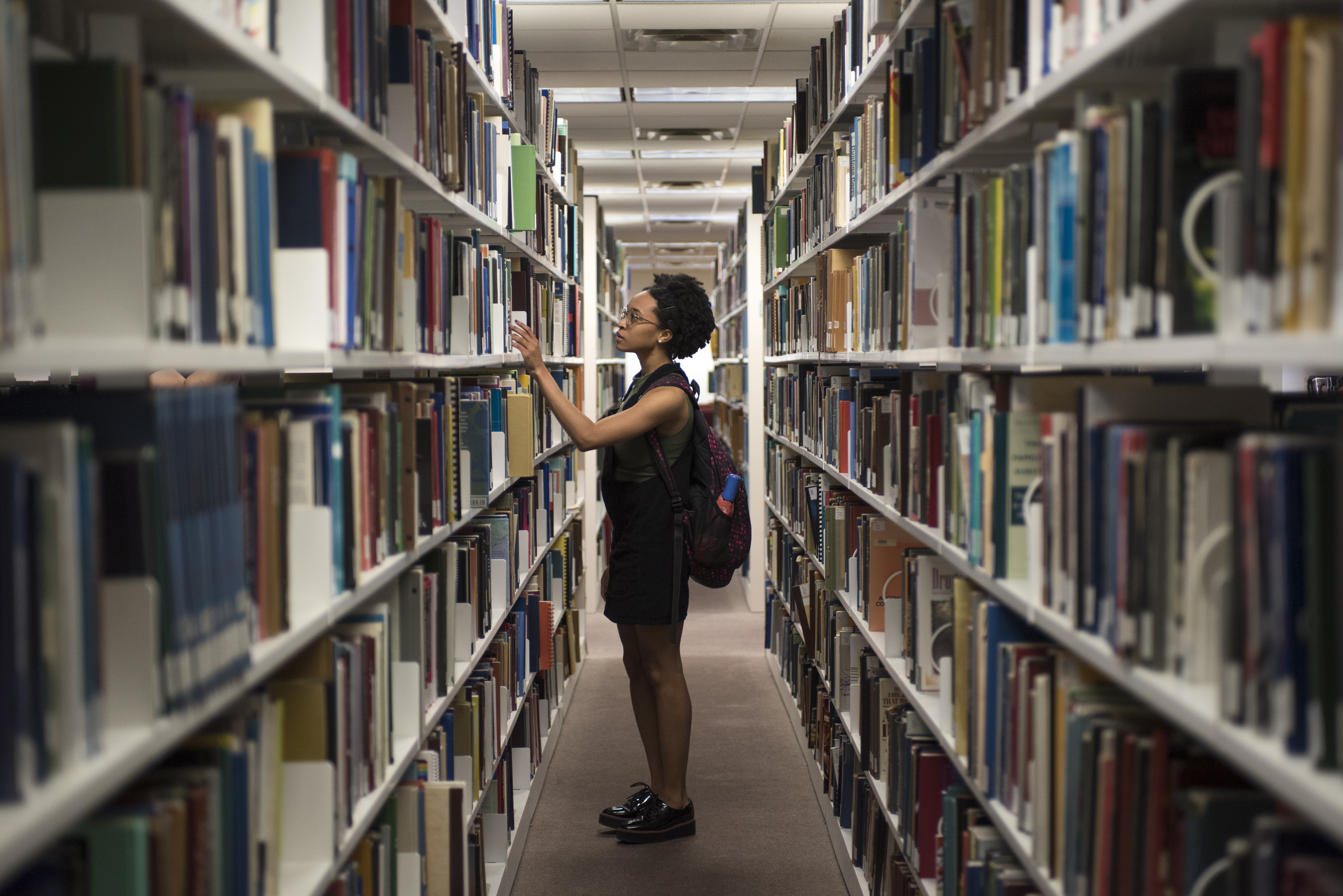 woman searching for books in the library