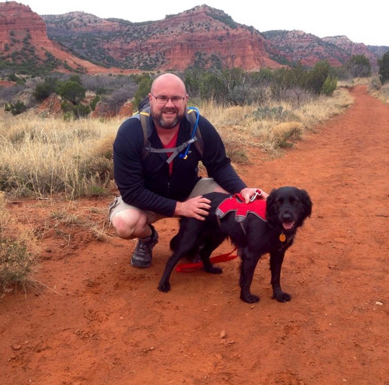 Dale and Lucy on a dirt road with red hills in the background. Location is Caprocks.