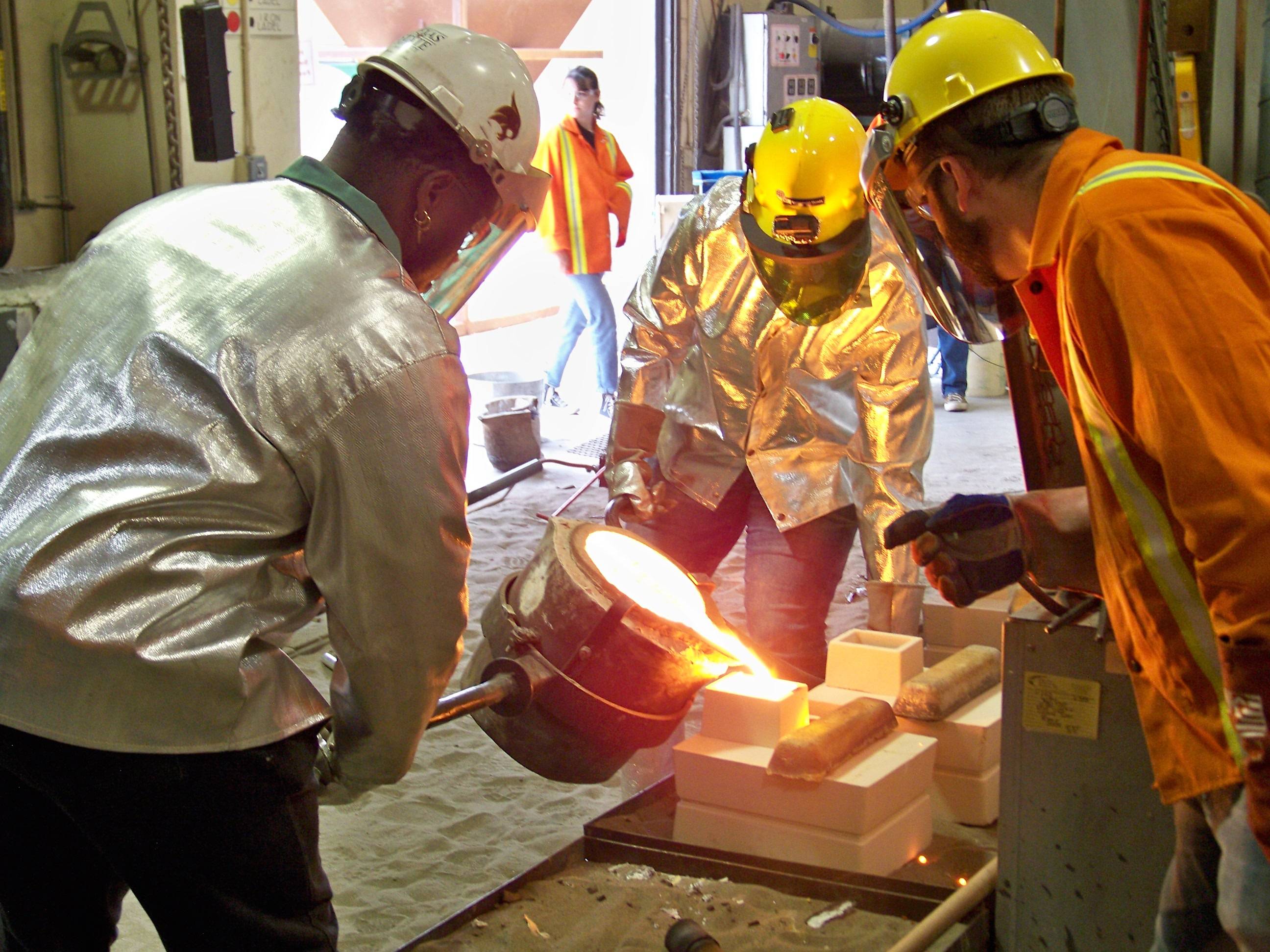 group of three pouring molten in sand frame