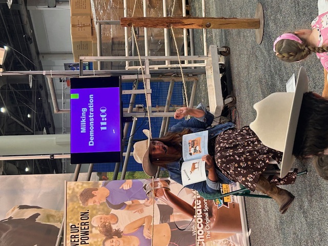 woman wearing cowboy hat reads book to small children