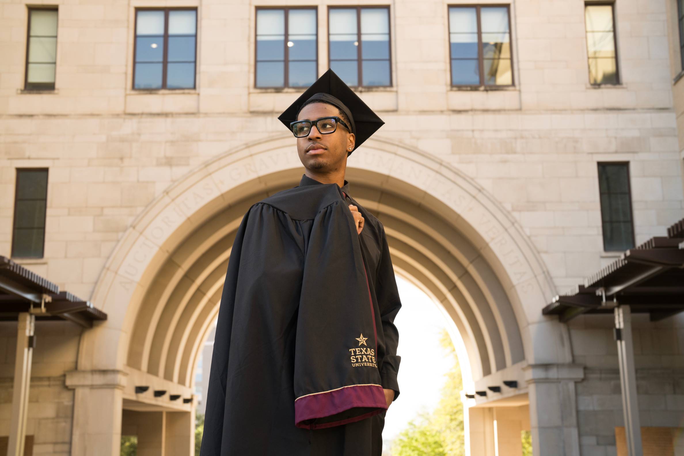 young man in cap and gown looks off into the distance