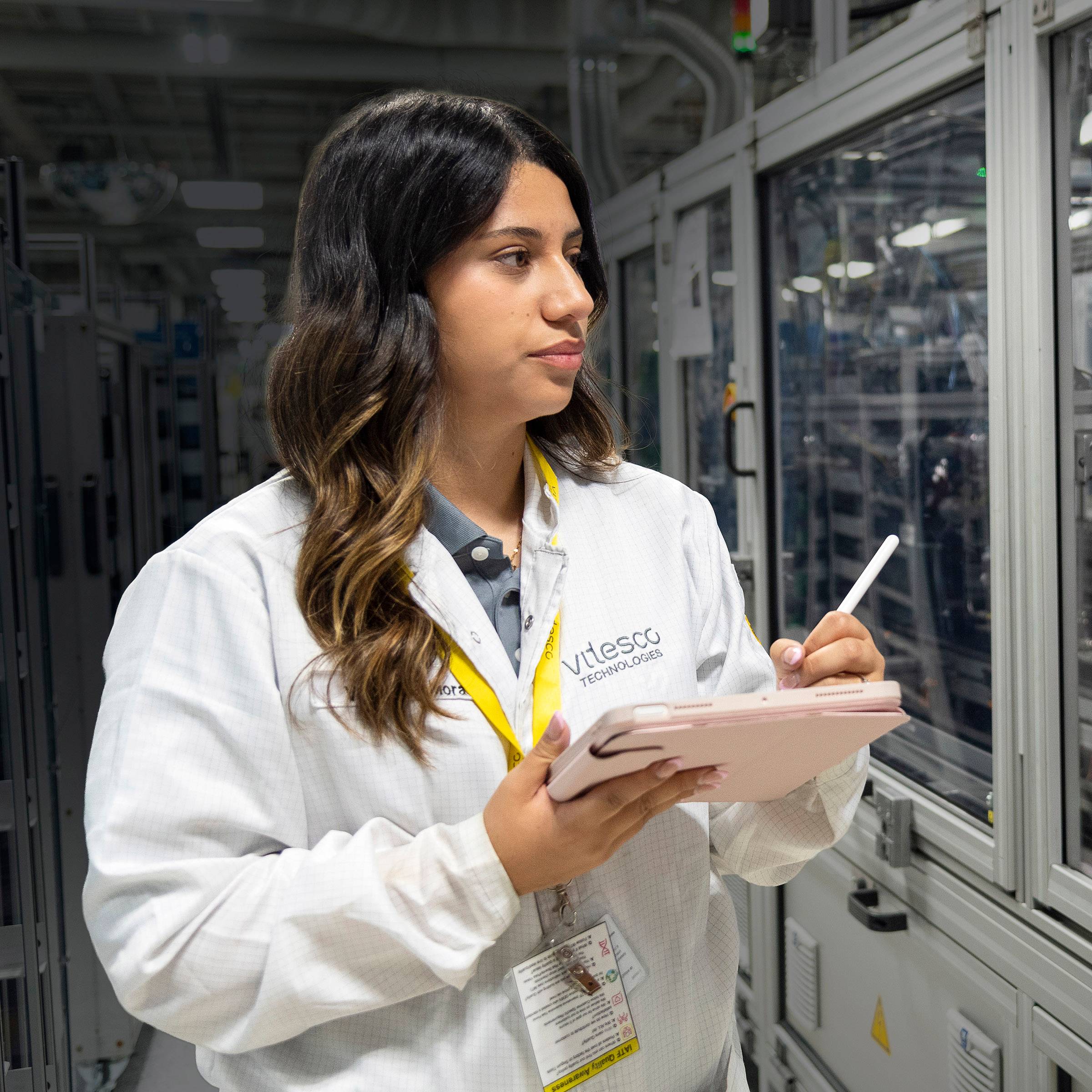 Student takes notes as they examine computer equipment.