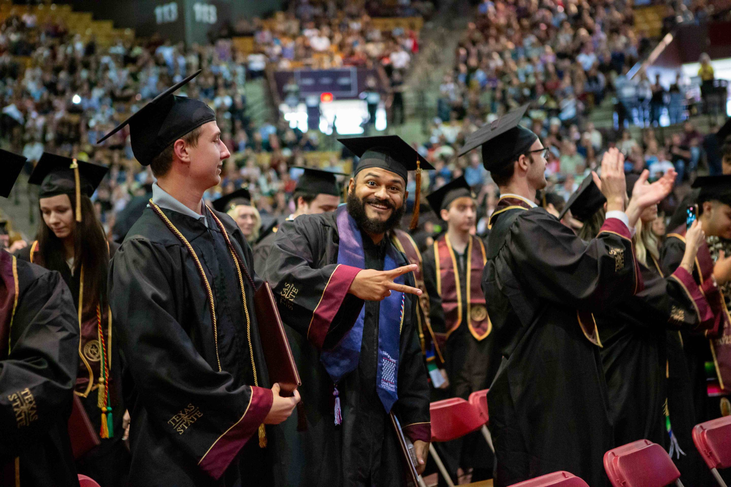 young man throws peace sign at graduation