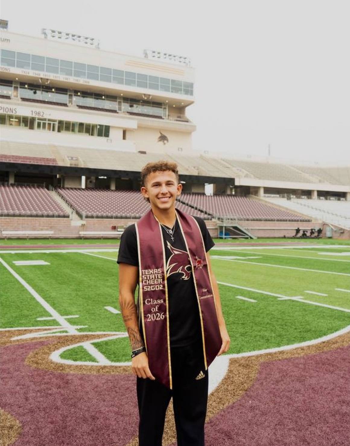 garrett smiles in his regalia with the texas state stadium in the background