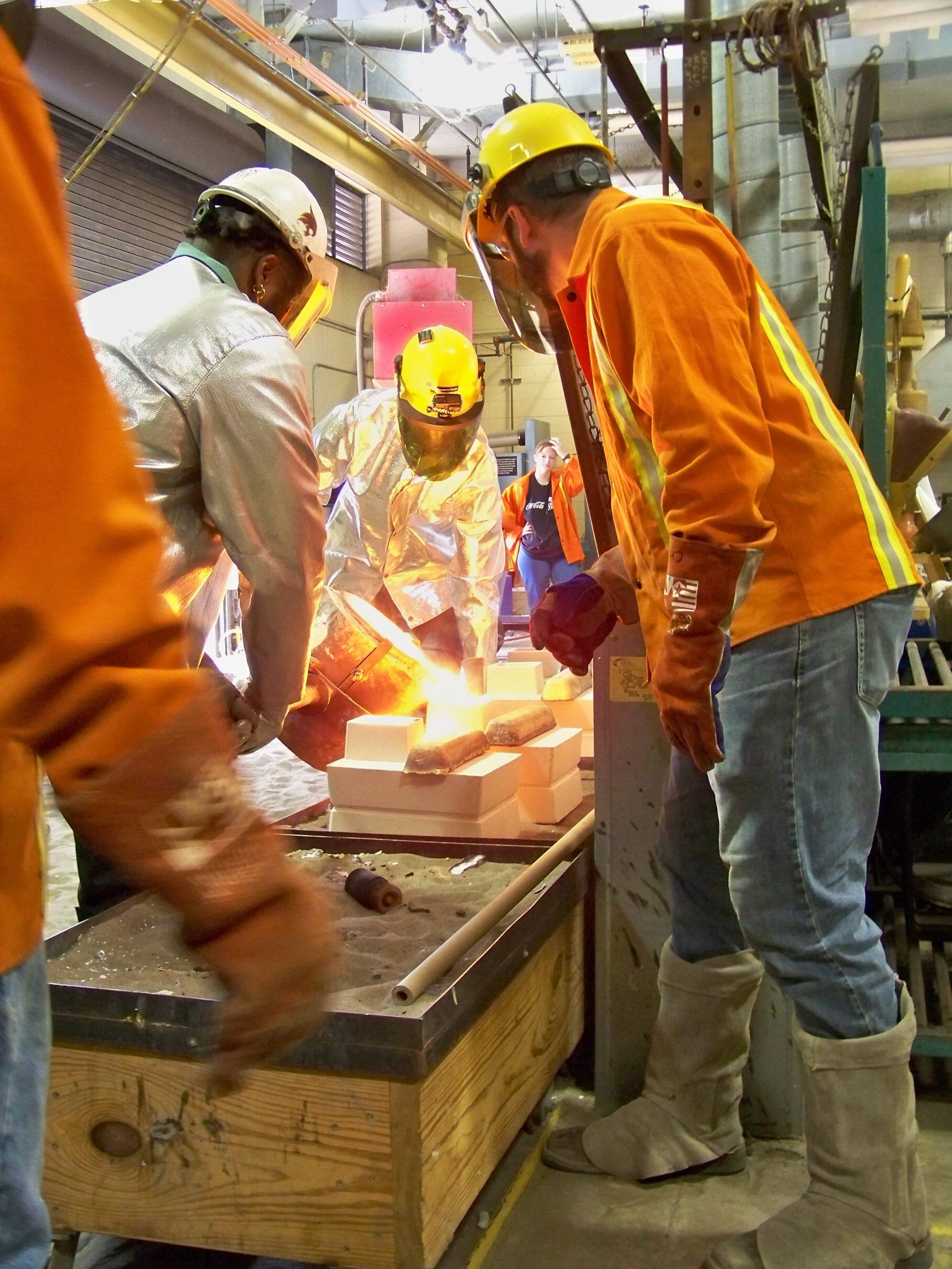 three men working with metal foundry
