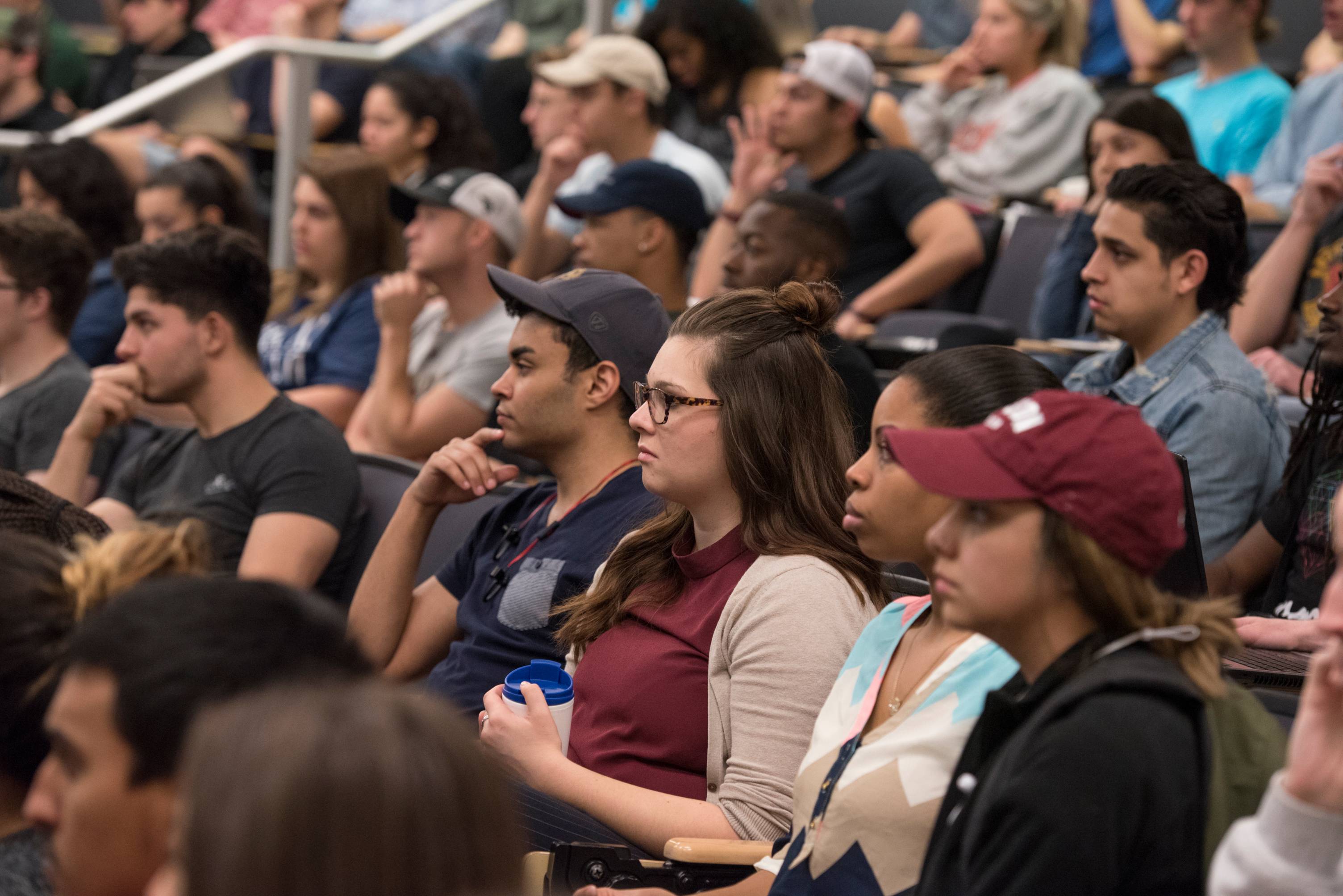 a group of over a dozen students sitting in ascending rows of seats. 