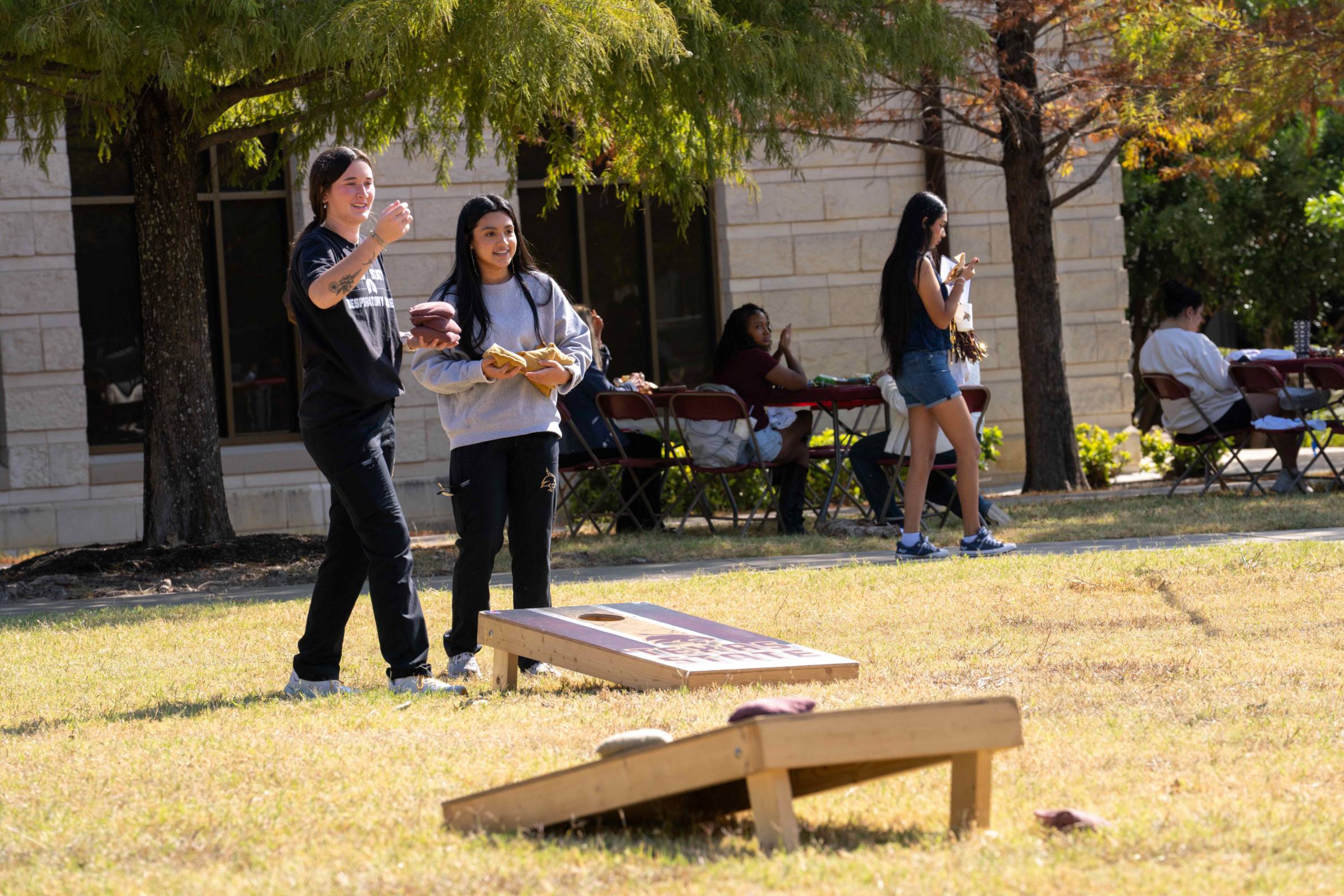 people play a game of cornhole on the round rock campus lawn