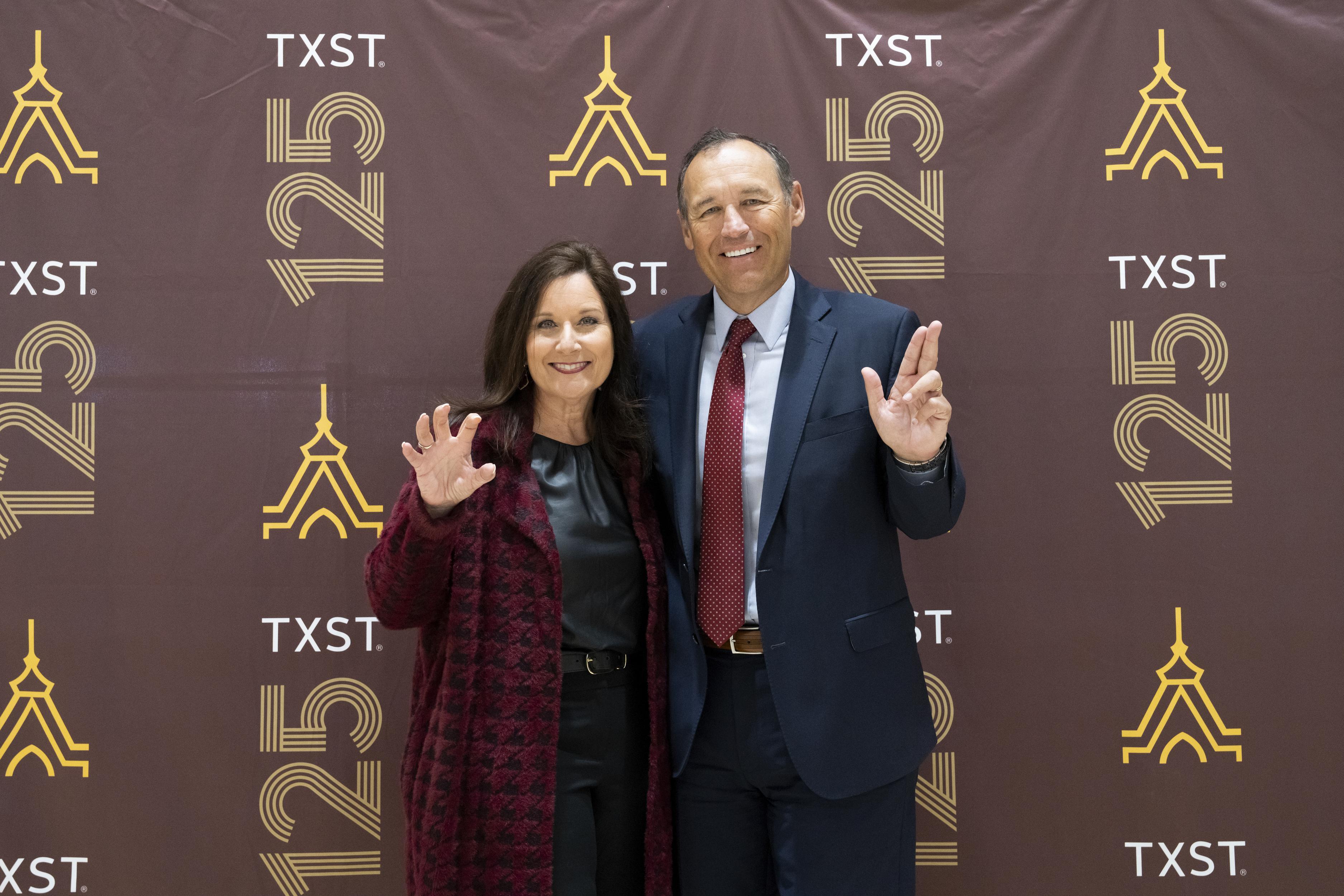 beth and kelly damphousse pose for photo with txst hand signs 