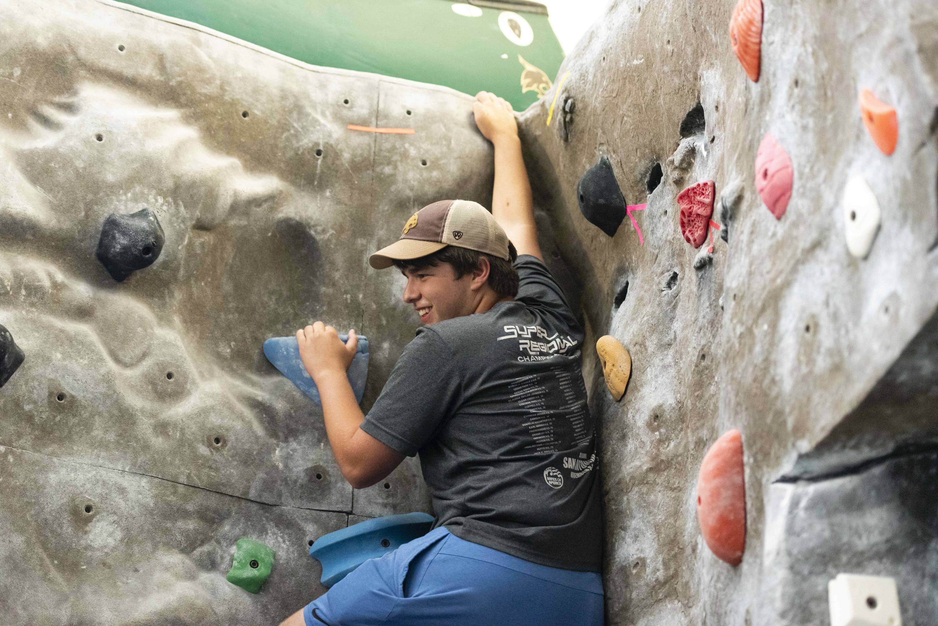 young man looks back as he climbs an indoor rock wall