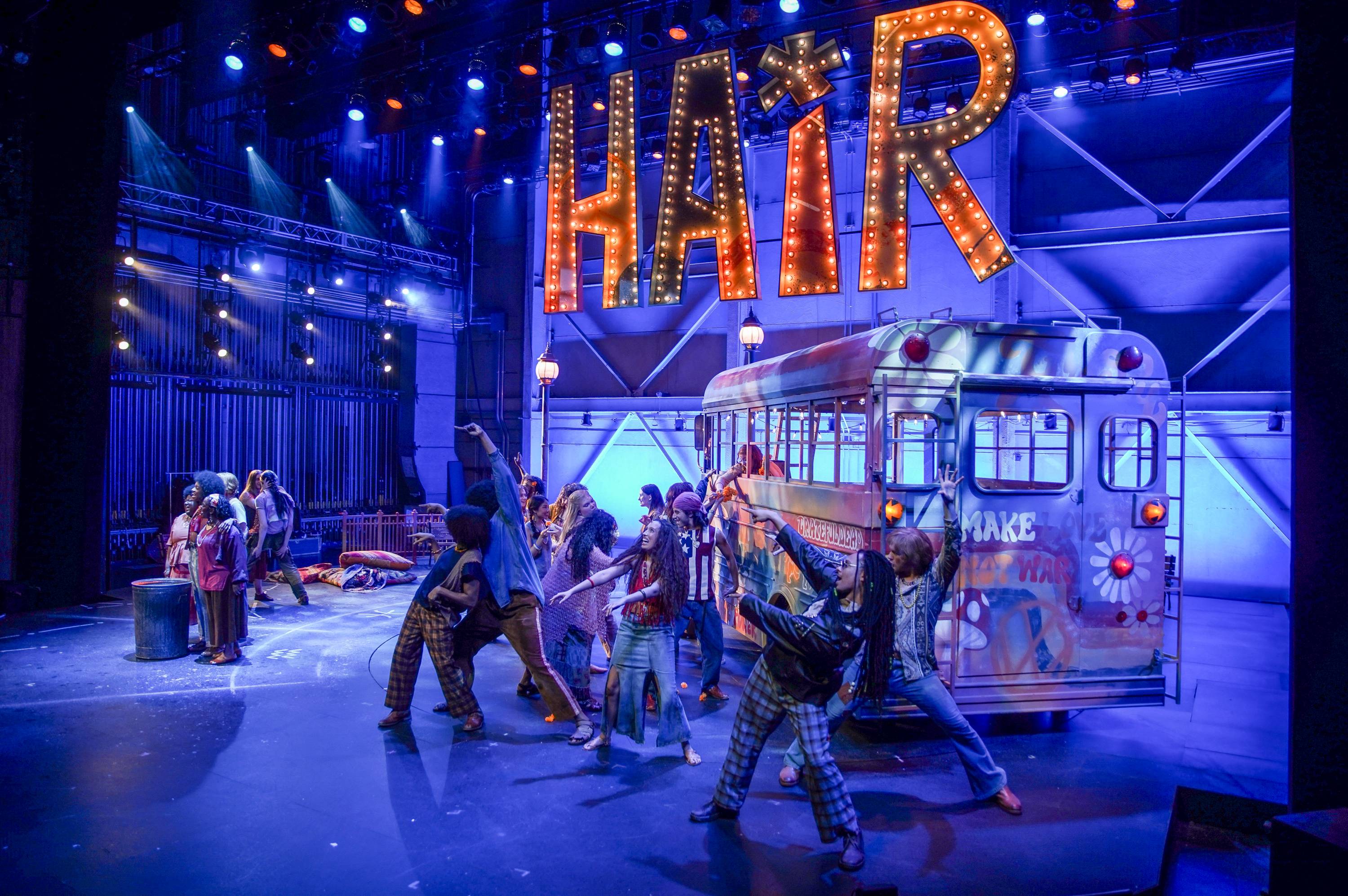 actors performing on stage for performance of "hair" with blue and orange lighting