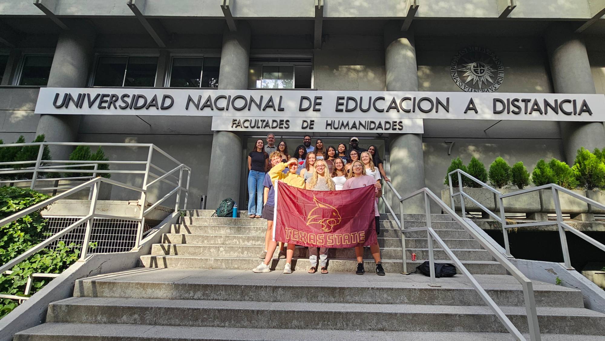 students with TXST flag in front of UNED building