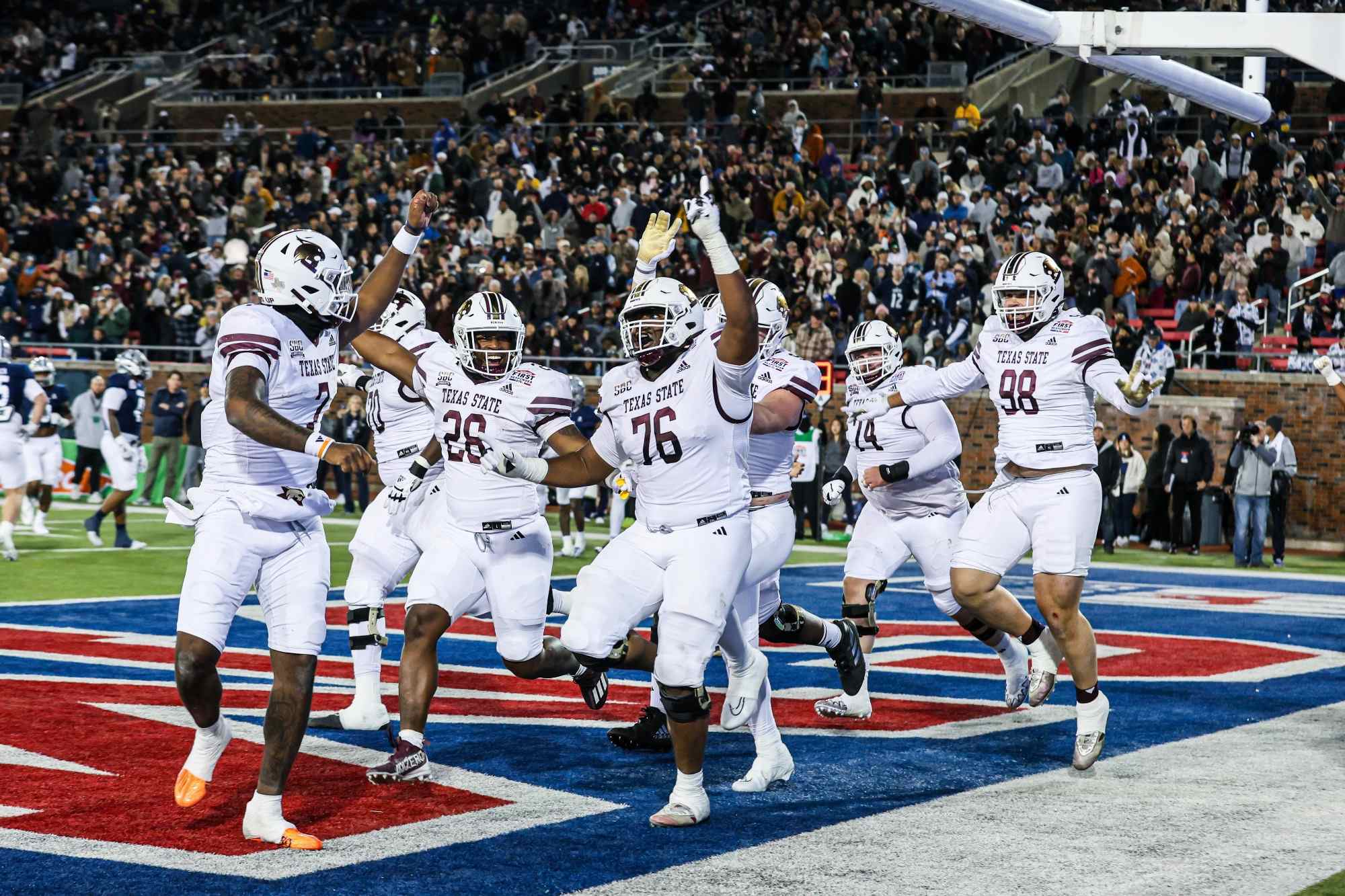 group of txst football players celebrate in the endzone