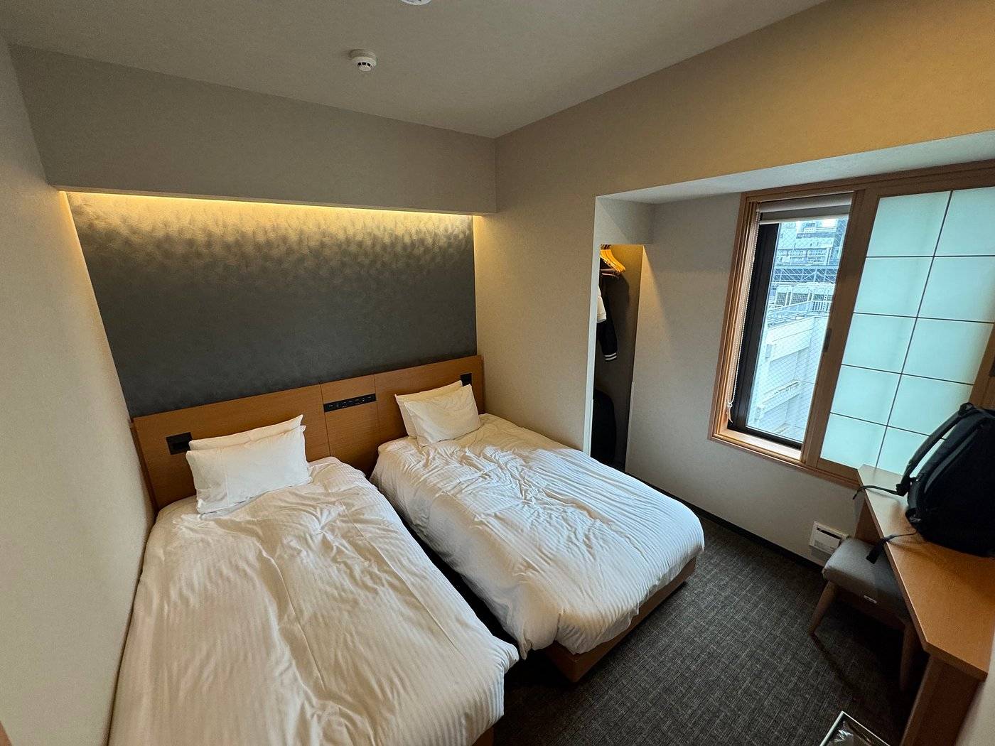 hotel bedroom with two beds, window and small desk
