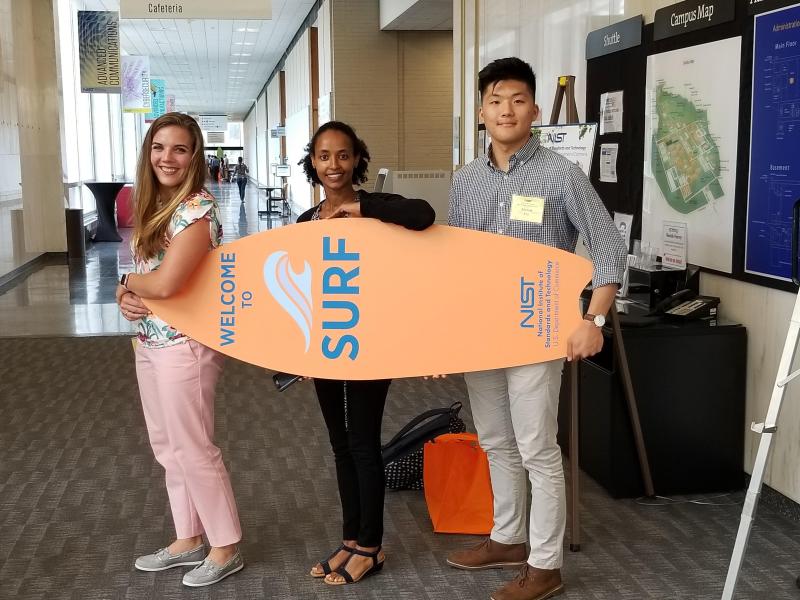 Students holding surf board with NIST SURF program logo