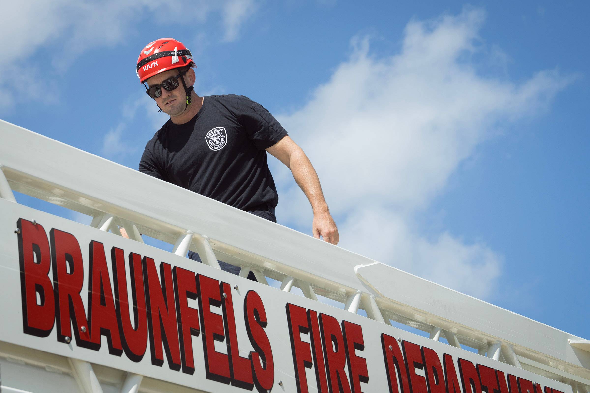 A firefighter climbs up a ladder on a truck.