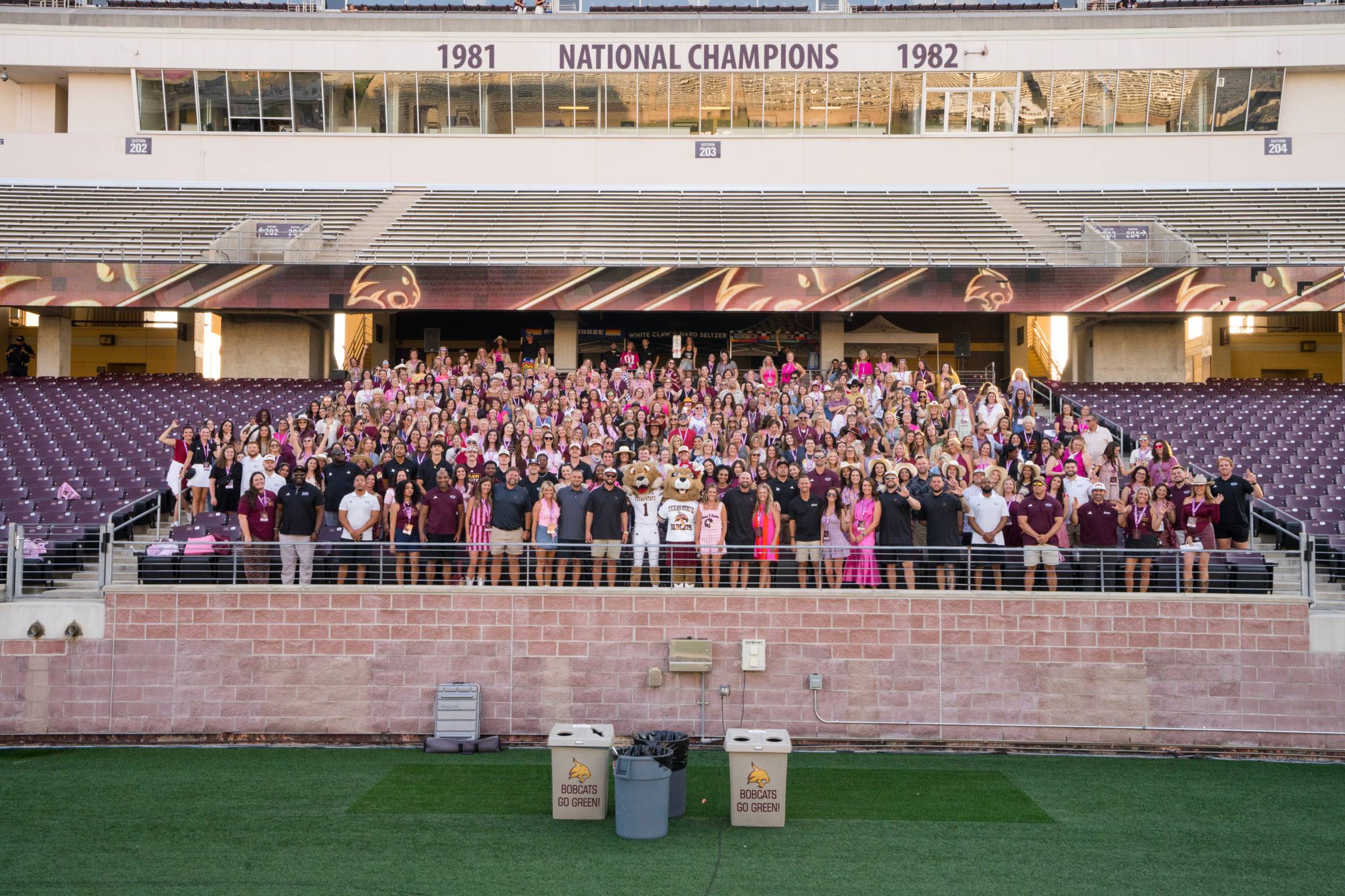 large group of people pose for group photo while standing in football stands