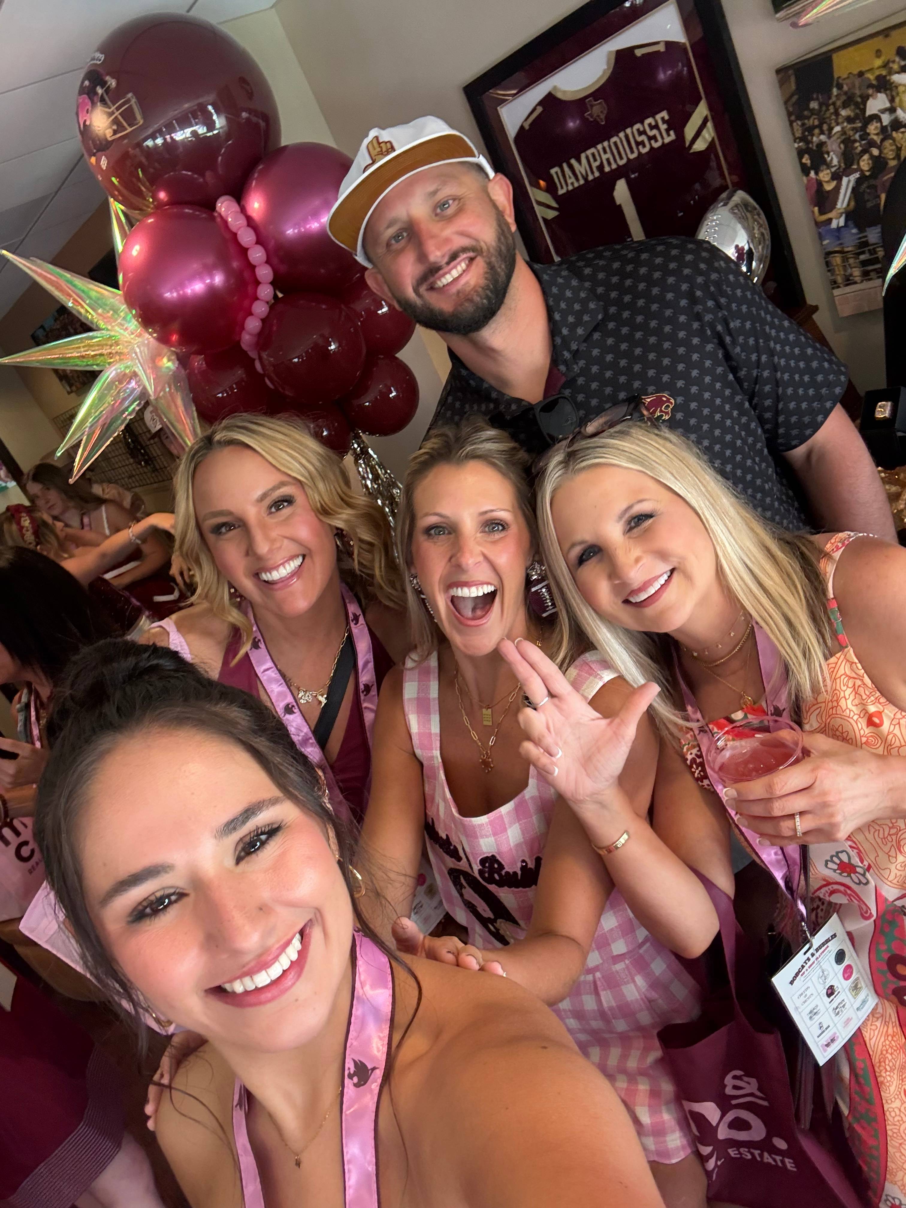 four women and man pose for group selfie