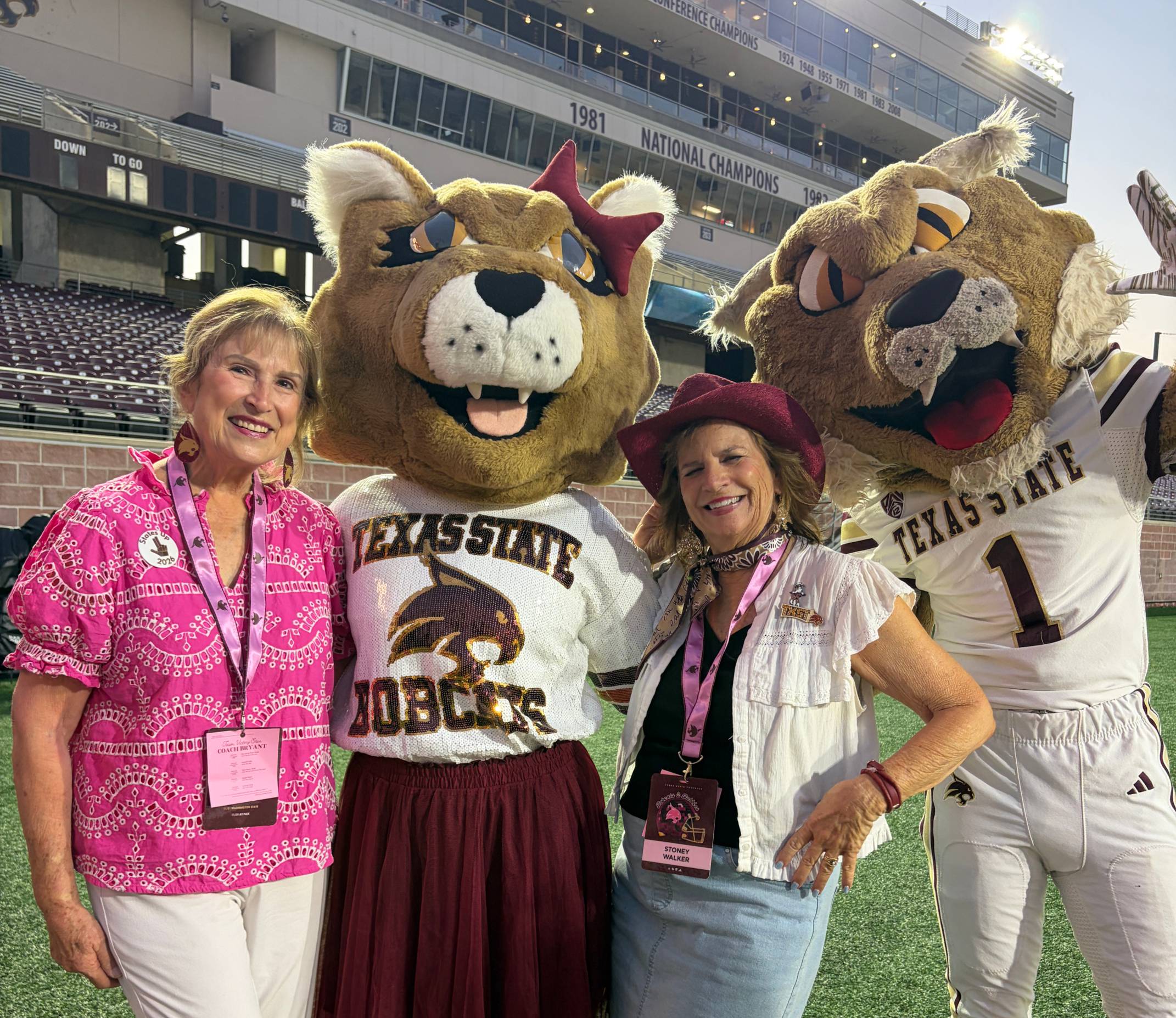 two women taking photo with female and male bobcat mascots