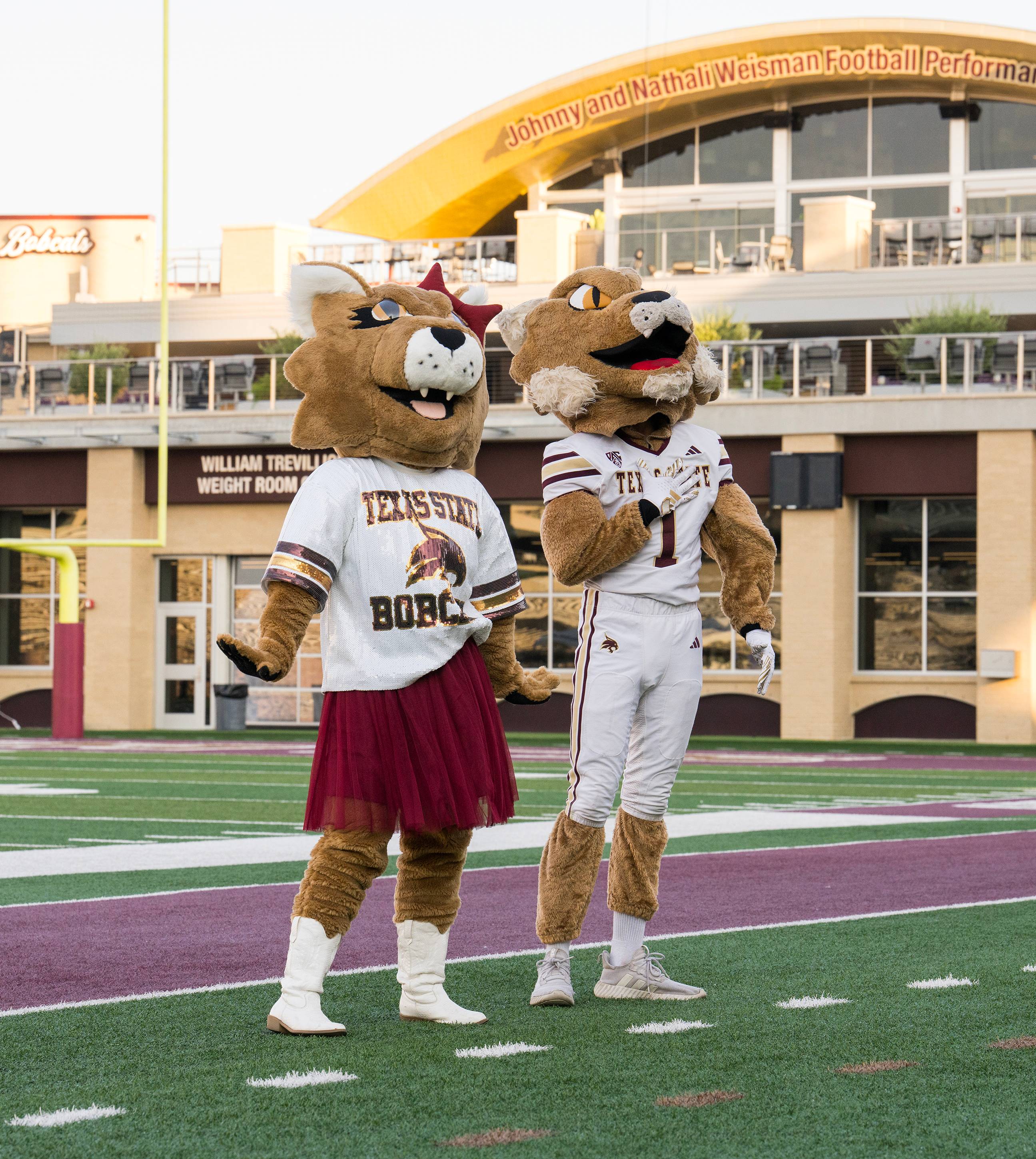 male and female boko mascots pose on football field