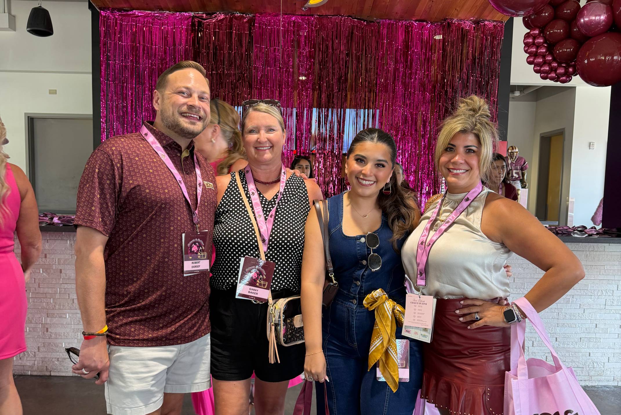 man and three women pose for photo in front of pink tinsel wall