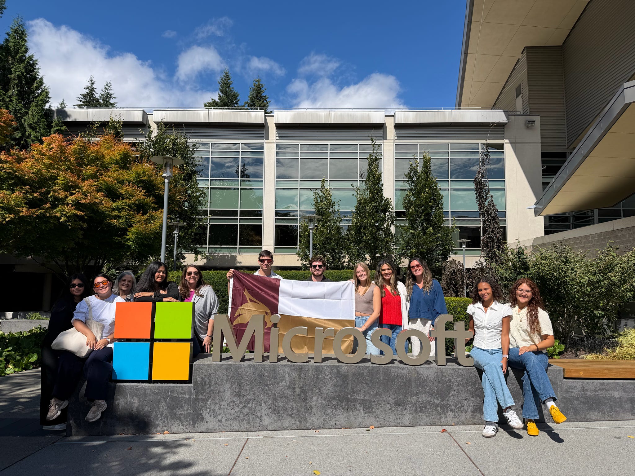 a group of texas state students and staff members standing in front of the Microsoft Logo
