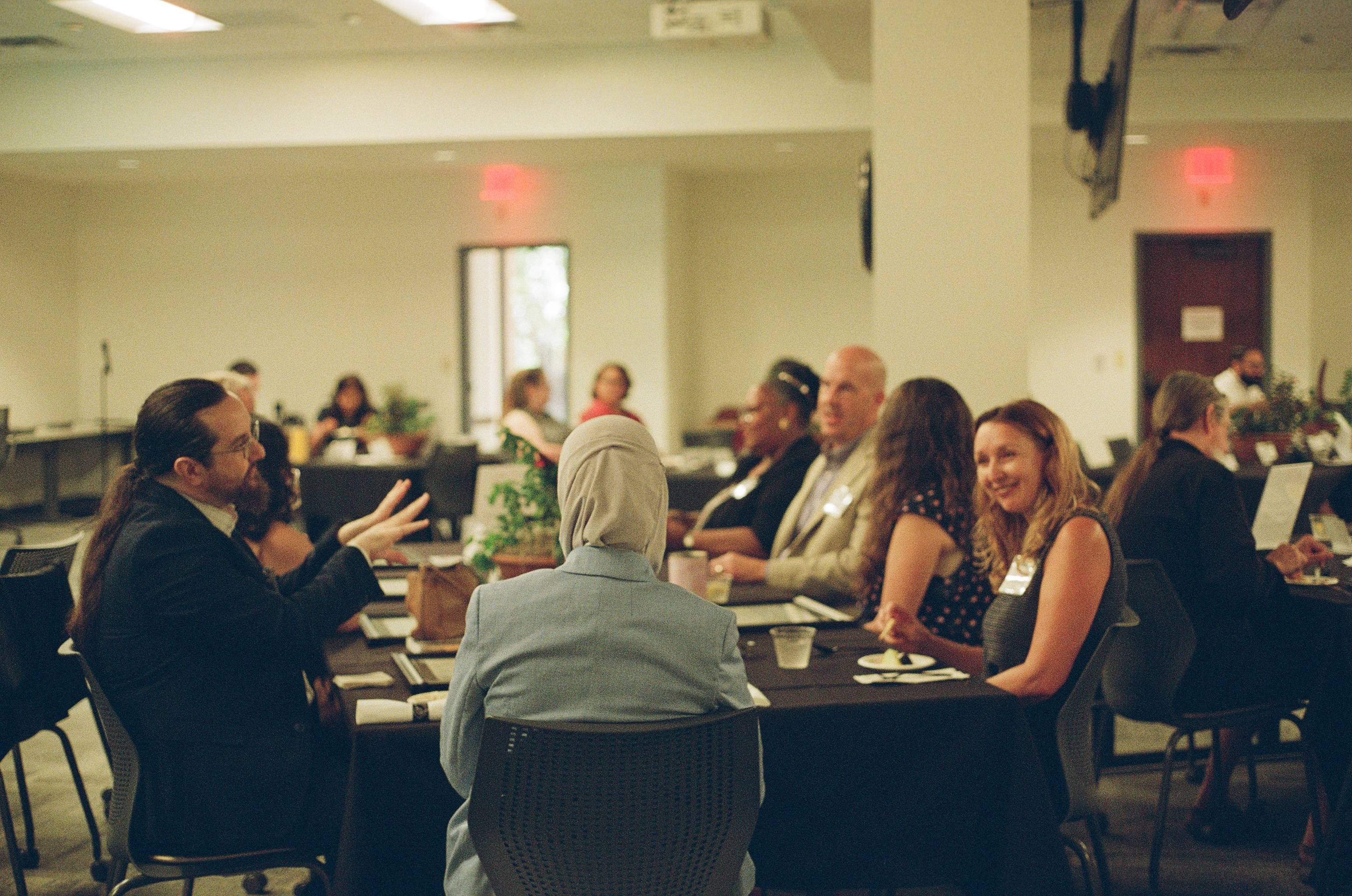 Faculty and chairs gathered at a table during the ACUE Pinning Ceremony