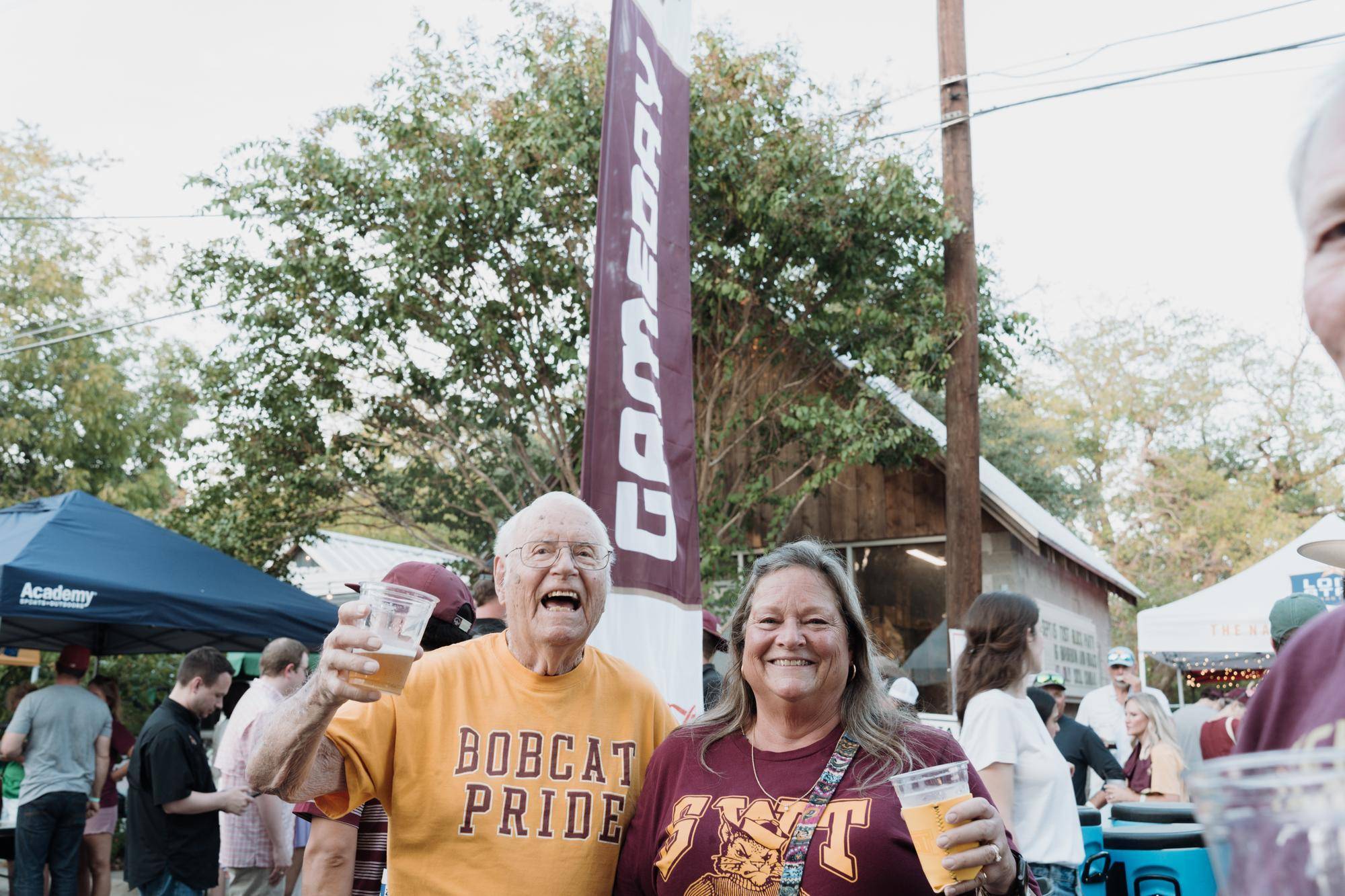 man and woman smiling while wearing txst tshirts