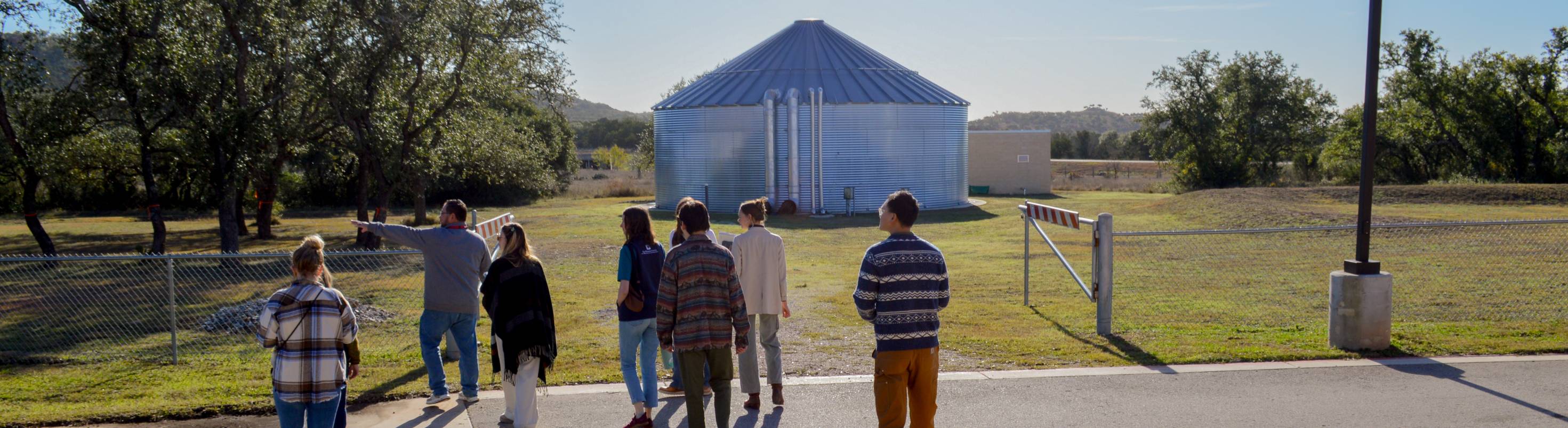 Meadows Center staff stand in front of rainwater harvesting tank at Blue Hole Primary School.