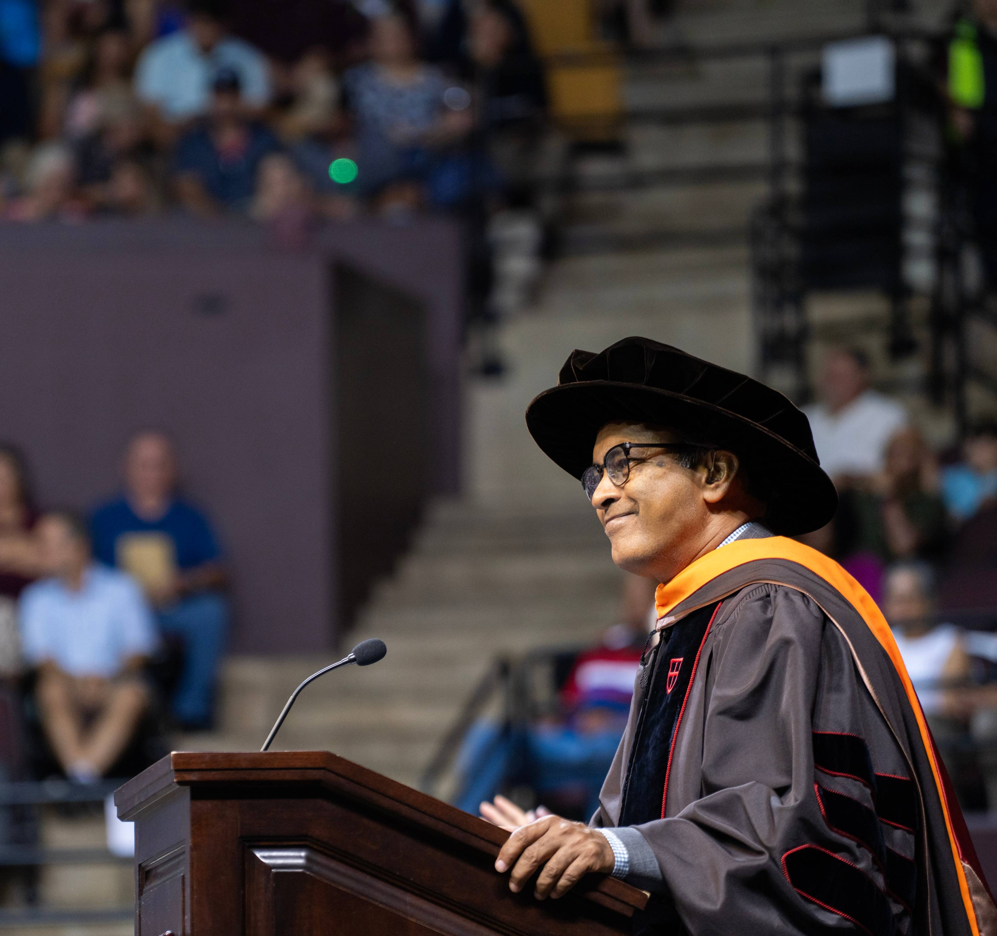 Pranesh Aswath, Provost and Executive Vice President, addresses the graduates and guests at commencement while wearing academic regalia.