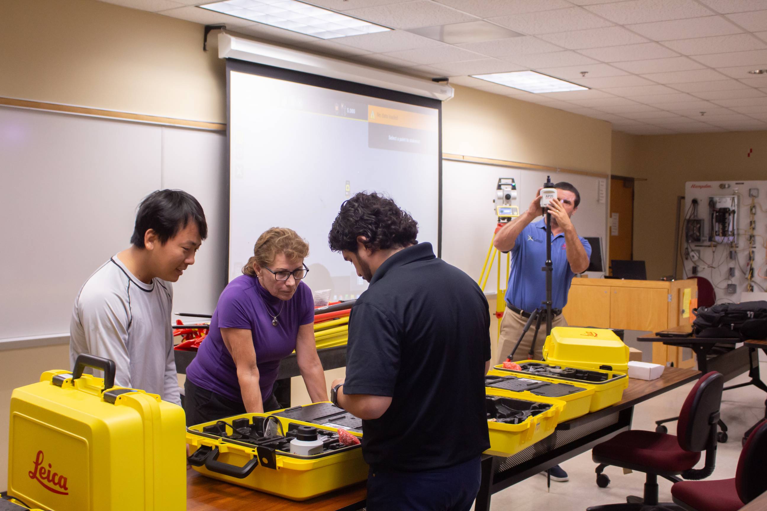four people looking at construction technology in classroom