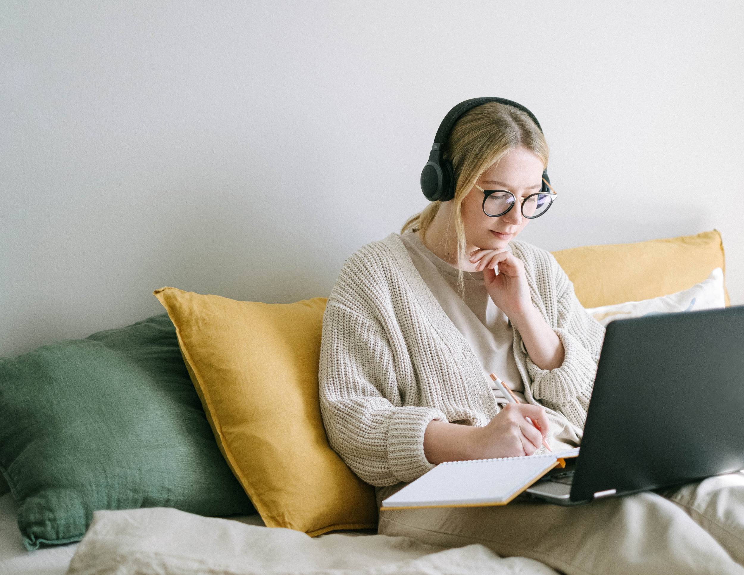 woman with glasses sitting in bed on laptop