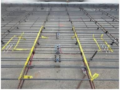 Steel reinforcement grid with sensors and wiring installed on a continuously reinforced concrete pavement (CRCP) test section for pavement performance monitoring.