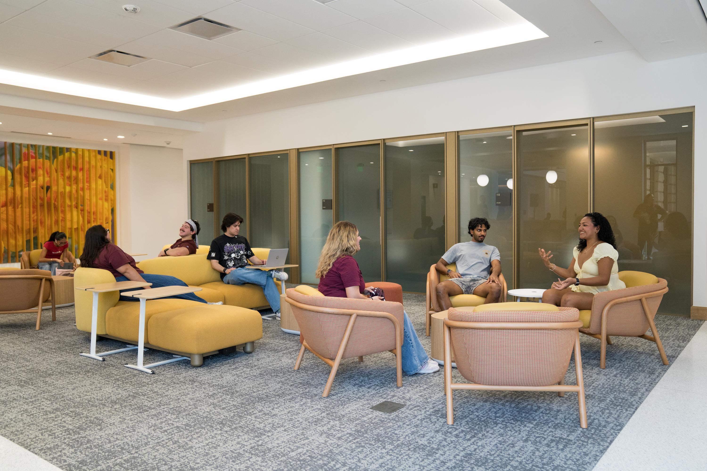 multiple students sit in lounge with biefe and yellow chairs